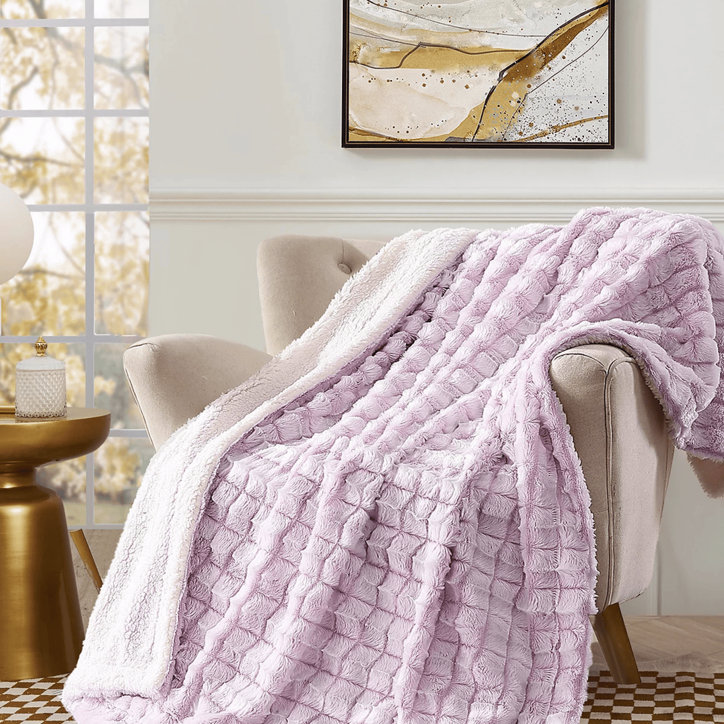The Mirabilia Boutique Custom Fall Throw Blanket, a plush light pink checkered design, is draped over a beige armchair in a sunlit room—perfect as a cozy autumn home gift.