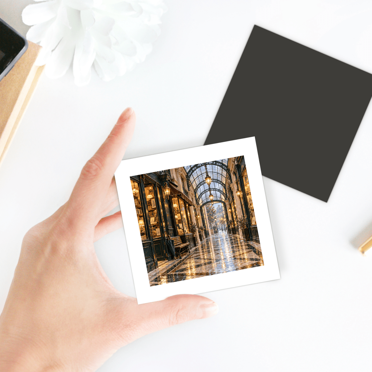 A hand holds a square Passage in the Rain Magnet featuring a photographic print of a glass-roofed Paris passage.