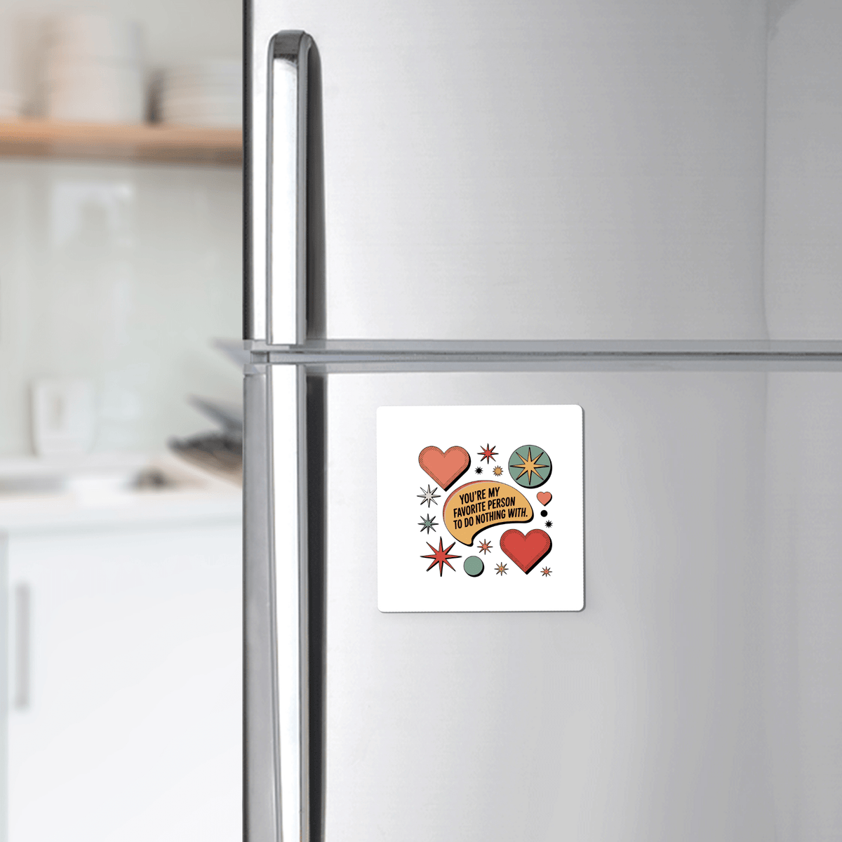 A silver fridge displays the Mirabilia Boutique Retro Love Quote Magnet, featuring red hearts, a lemon slice, and starbursts with the quote “You’ve got to have passion to do anything with it,” in a modern kitchen.