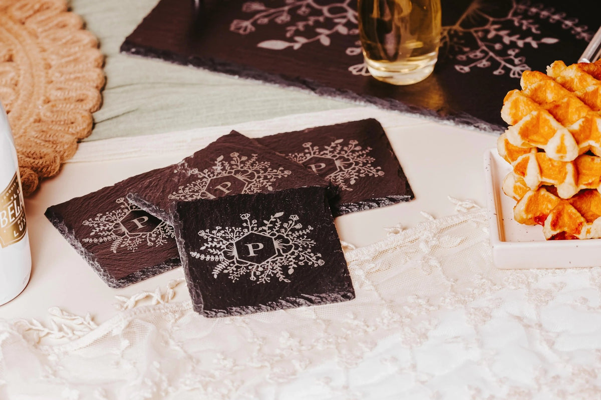 Four black slate coasters with an engraved monogram “P” design from Mirabilia Boutique add a personalized touch to your breakfast table—ideal as a housewarming gift.