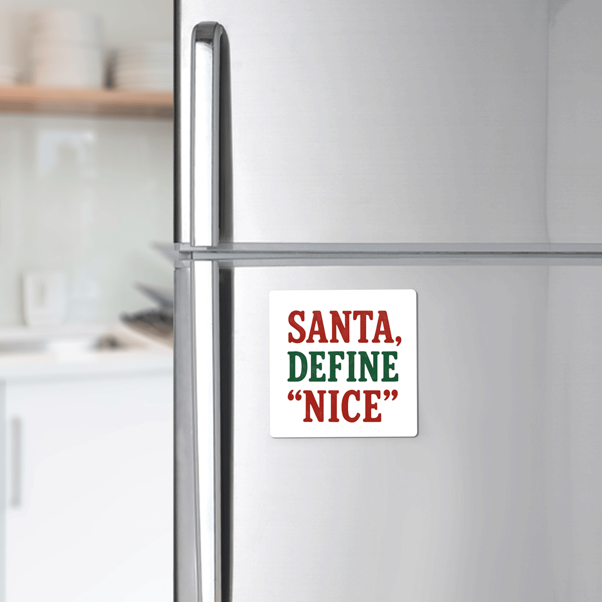 A Mirabilia Boutique "Santa Define Nice" magnet—featuring bold red and green text—is a funny Christmas fridge gift, perfect as a stocking stuffer or holiday gag from their collection. The softly blurred kitchen adds festive charm.