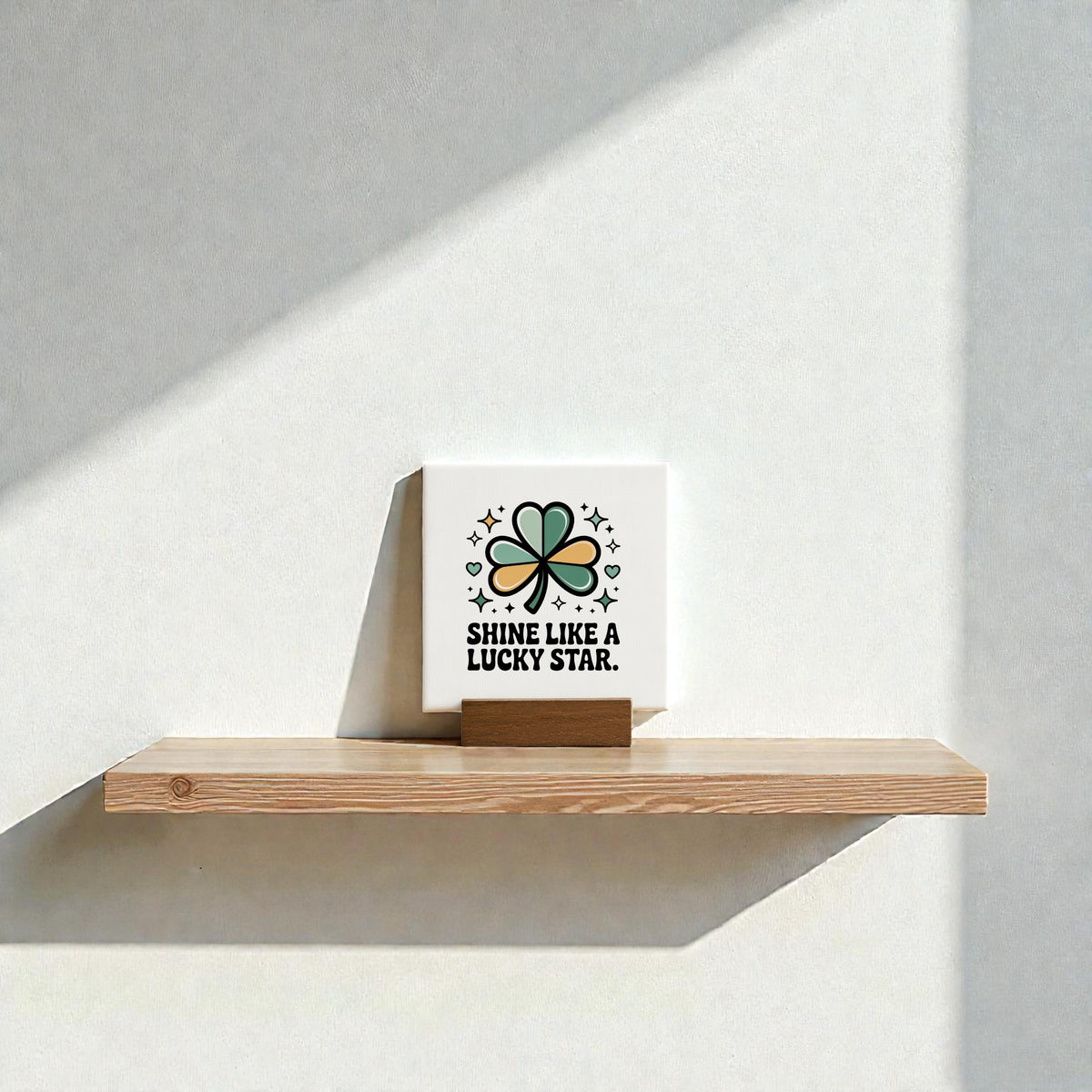 The Mirabilia Boutique Shine Like a Lucky Star Canvas Sign (4x4) features a four-leaf clover and stars, making it perfect St. Patrick’s Day decor. Sunlight casts playful shadows on the wall for added charm.