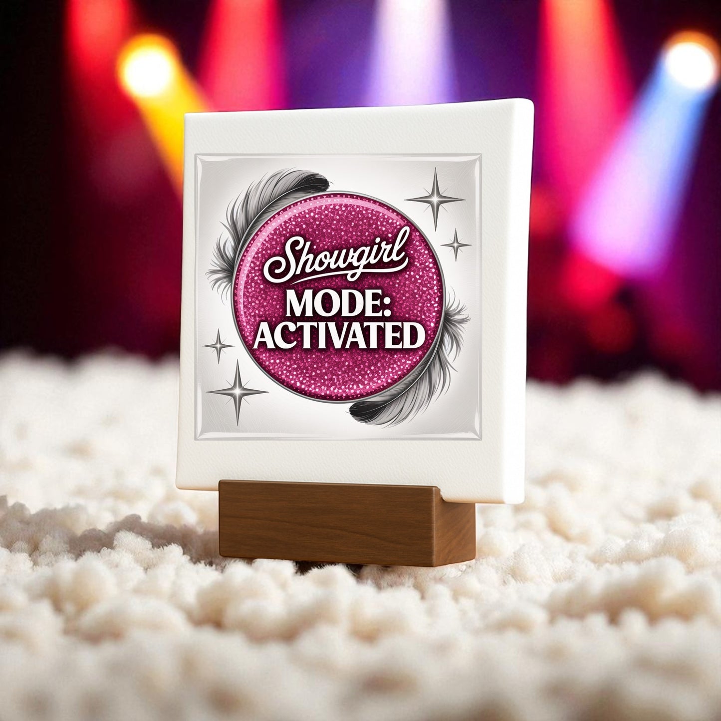 Add sparkle to your space with the Showgirl Mode Activated Mini Sign by Mirabilia Boutique. This glam pink sign features bold text, black feathers, stars, and stands on a wooden base—perfect for chic table decor.