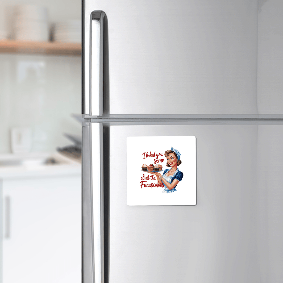 A Mirabilia Boutique Fucupcakes Magnet, a 3x3" UV printed retro fridge magnet, shows a vintage woman with the text "I Baked You Some Shut the Fucupcakes," displayed on a stainless steel fridge with kitchen shelves in the background.
