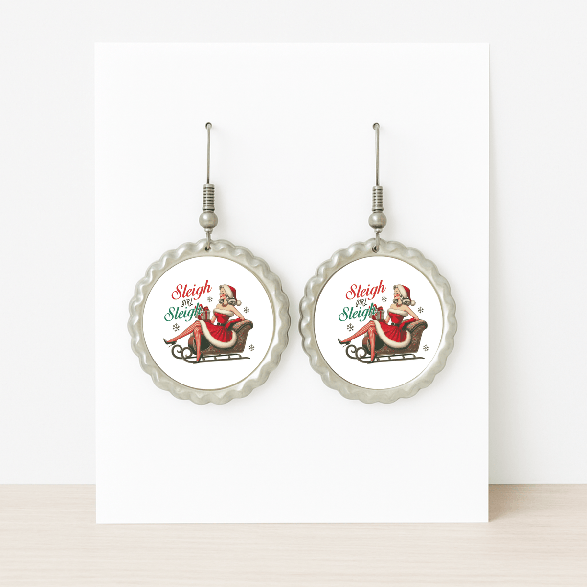 Mirabilia Boutique’s Sleigh Girl Sleigh Earrings feature a vintage Santa-hat woman on a sleigh with “Sleigh Sleigh Sleigh” in festive colors—a retro Christmas jewelry piece perfect for the holiday season.