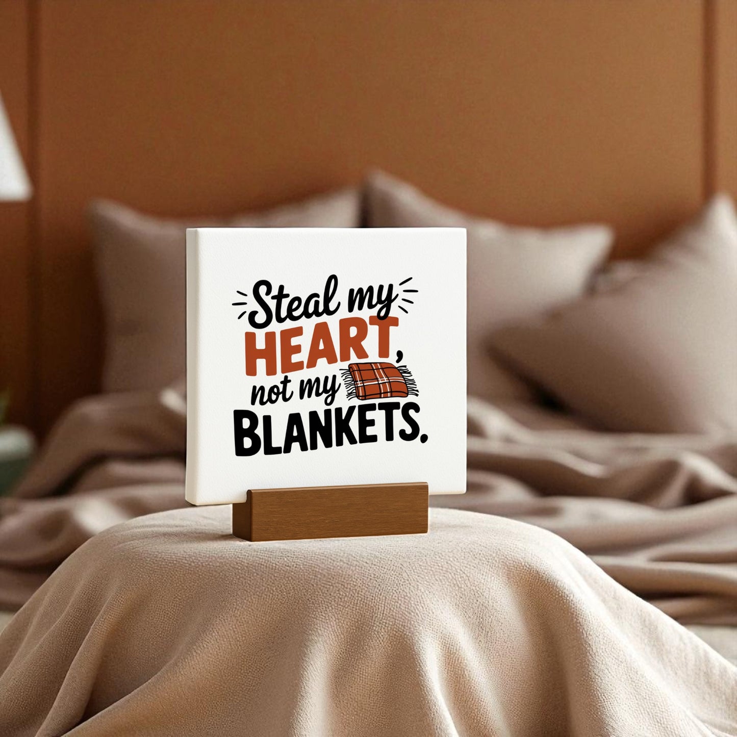 The Steal My Heart Mini Sign by Mirabilia Boutique, perfect for couples, sits on a neatly made bed with soft beige bedding and chic decor. Its witty "Steal my heart, not my blankets" message adds charm to any romantic bedroom.