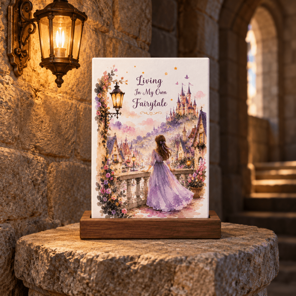 A Living in My Own Fairytale Mini Canvas displayed on a wooden stand, depicting a woman in a purple dress standing on a stone balcony overlooking a village and castle.
