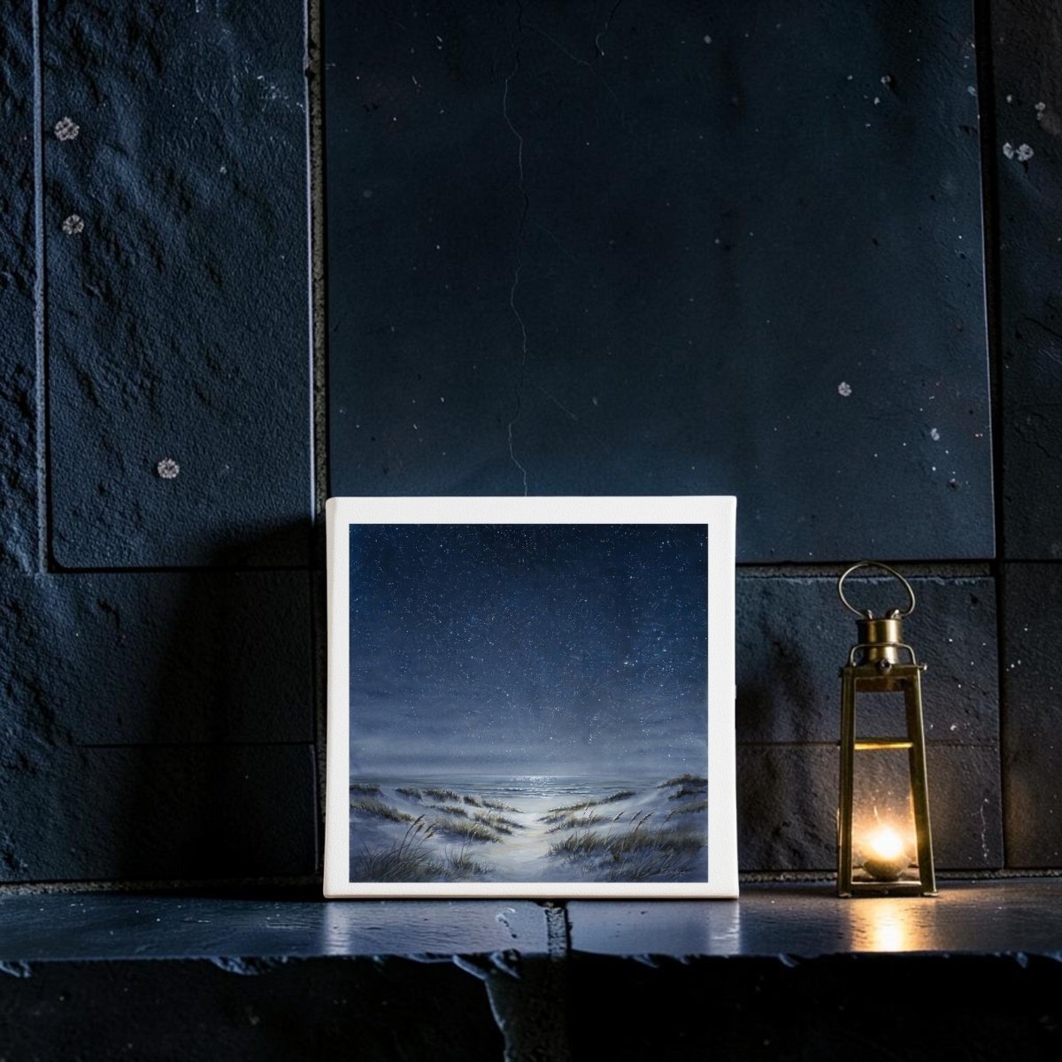 An 8x8 canvas titled “The Sea Keeps Its Own Stars” by Mirabilia Boutique rests on a dark stone mantle beside a lit lantern, infusing the space with serene coastal decor and the tranquil charm of starry night wall art.