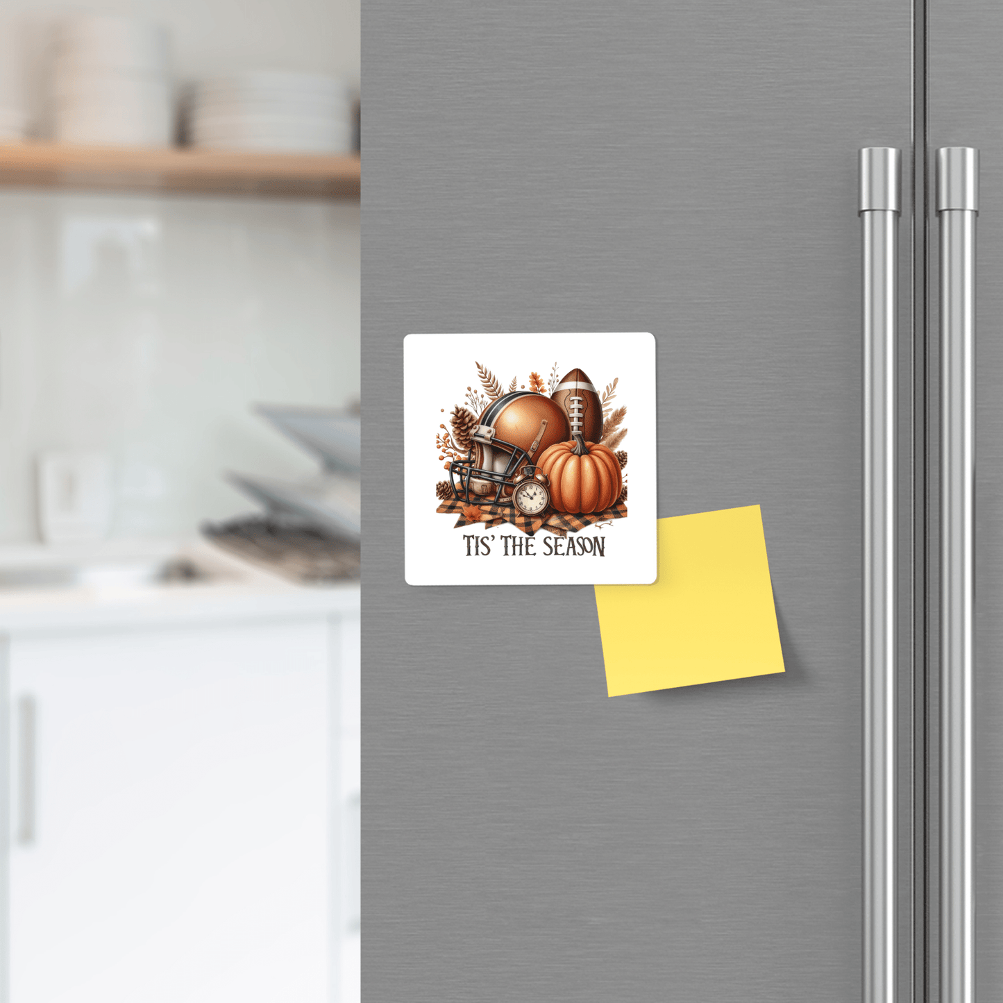 A refrigerator displays the "Tis’ the Season Magnet" by Mirabilia Boutique, featuring football and pumpkin designs for fall. A blank yellow sticky note and kitchen shelves with dishes are also in view, perfect for festive football kitchen decor.