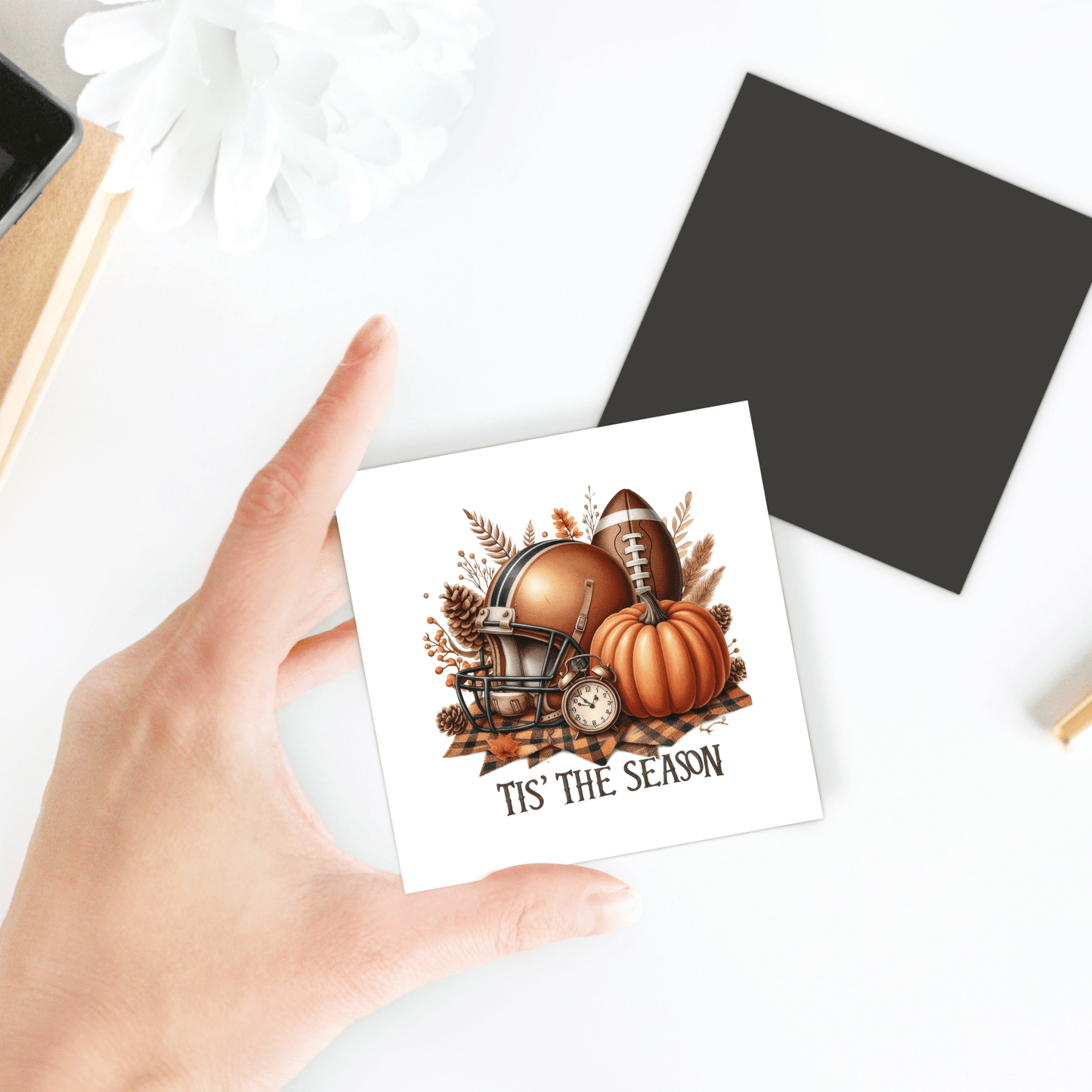 A hand holds the Mirabilia Boutique "Tis’ the Season Magnet"—a festive fall football pumpkin decor for your fridge, perfect as a Thanksgiving or autumn kitchen accent.