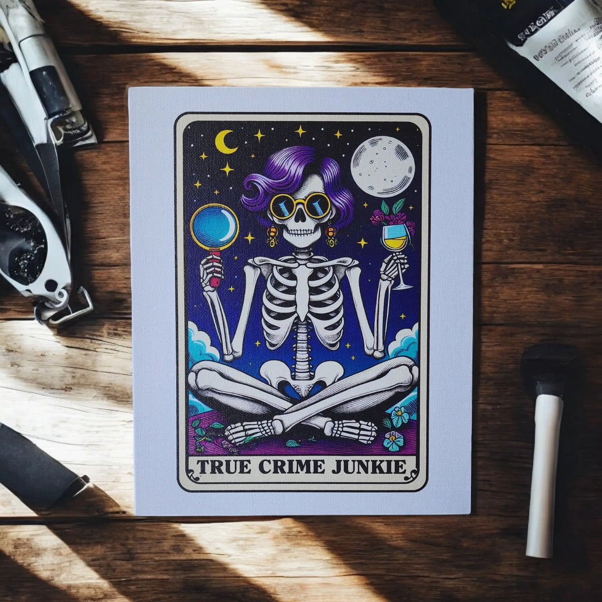 Mirabilia Boutique’s True Crime Junkie Canvas Art features a skeleton with purple hair, sunglasses, a magnifying glass and wine, under the moon and stars. This 8x10 UV printed wall décor is a perfect funny gift for podcast lovers.