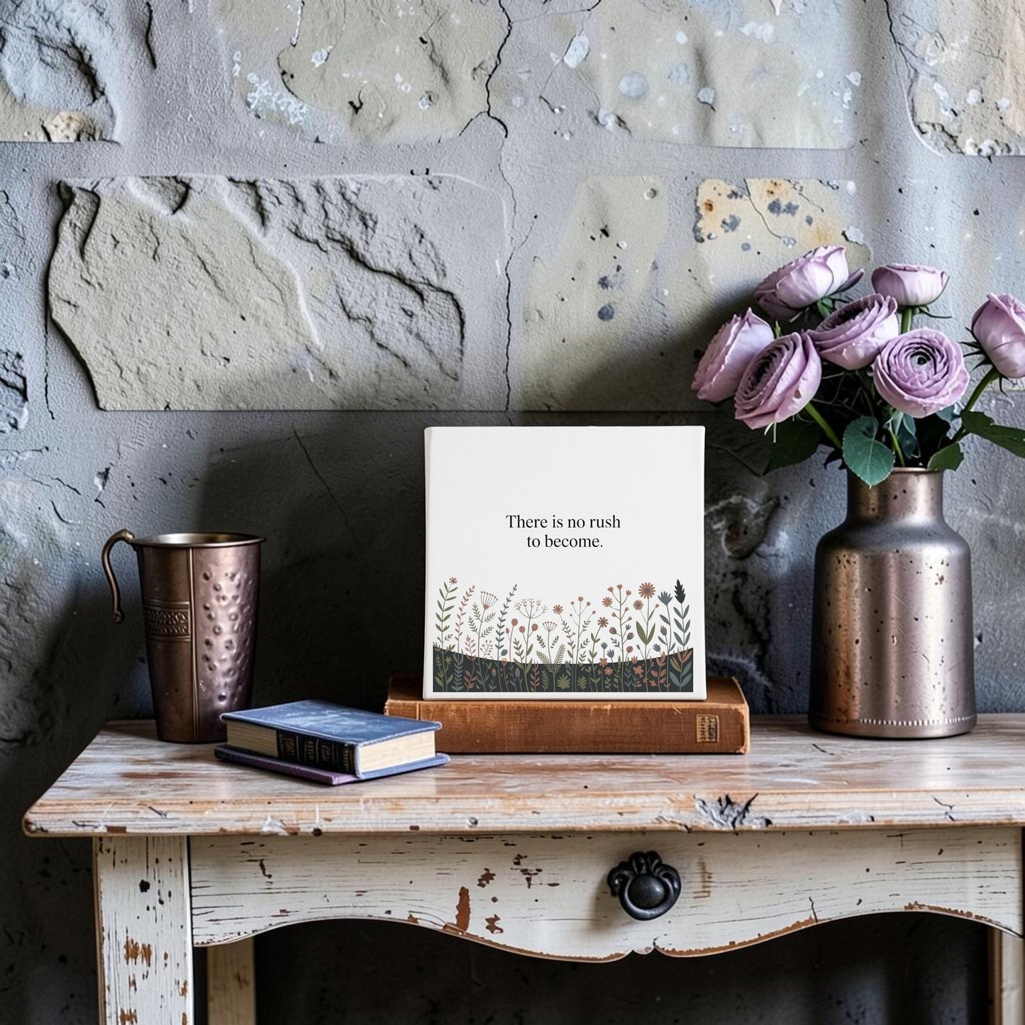 The "There Is No Rush to Become" Canvas Art by Mirabilia Boutique features a rustic wooden table, books, a metallic cup, a copper vase of purple roses, and an inspiring quote—ideal motivational home decor or thoughtful gift.