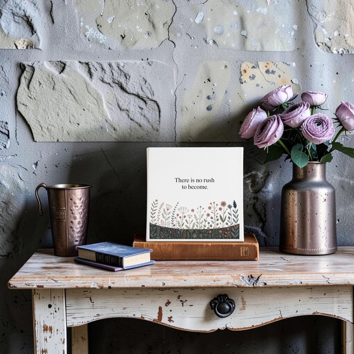 The "There Is No Rush to Become" Canvas Art by Mirabilia Boutique features a rustic wooden table, books, a metallic cup, a copper vase of purple roses, and an inspiring quote—ideal motivational home decor or thoughtful gift.