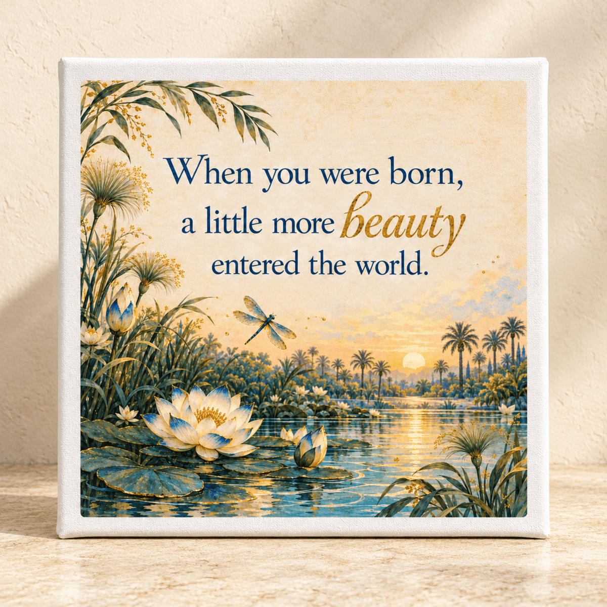 A Little More Beauty Canvas from Mirabilia Boutique featuring a pond with lotus flowers and a dragonfly at sunset, inscribed with, “When you were born, a little more beauty entered the world.”