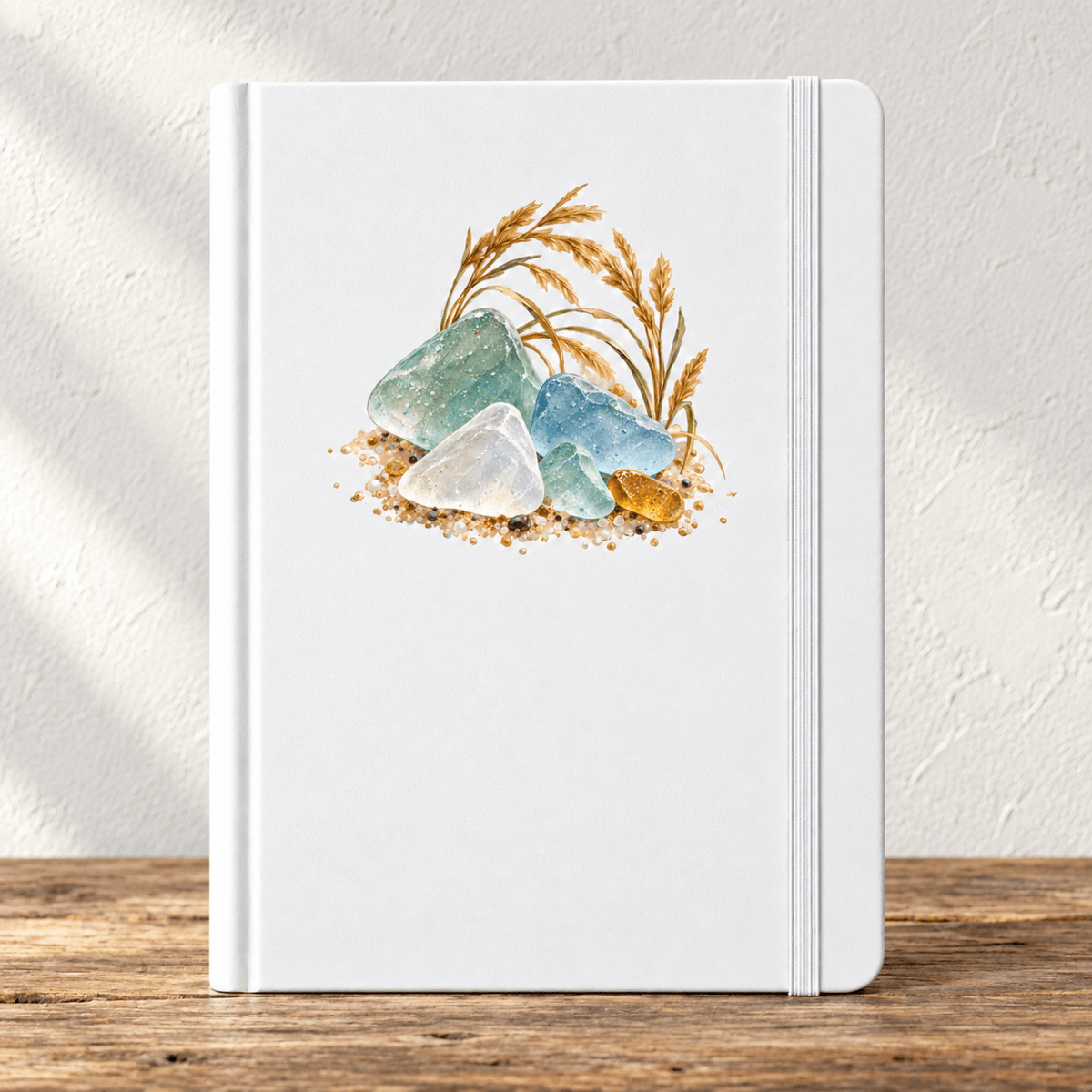 A Little of the Shore Journal, an A5 white journal with a watercolor illustration of sea glass, sand, and beach grass on the cover.