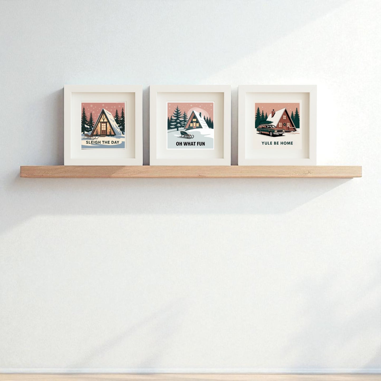 The Mid-Century Modern A-Frame Cabin Sign Trio | Sleigh the Day Set by Mirabilia Boutique features three framed prints with winter cabin scenes and holiday puns—"Sleigh The Day," "Oh What Fun," and "Yule Be Home"—perfect for festive decor.