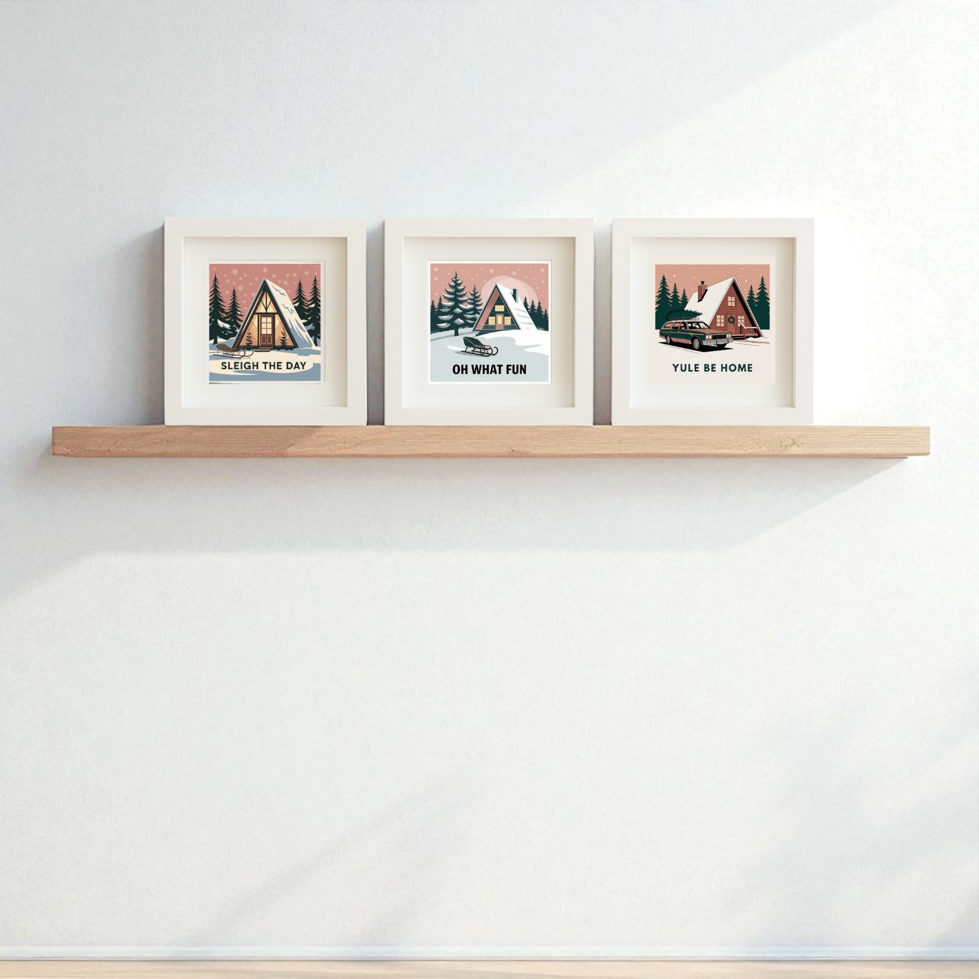 The Mid-Century Modern A-Frame Cabin Sign Trio | Sleigh the Day Set by Mirabilia Boutique features three framed prints with winter cabin scenes and holiday puns—"Sleigh The Day," "Oh What Fun," and "Yule Be Home"—perfect for festive decor.