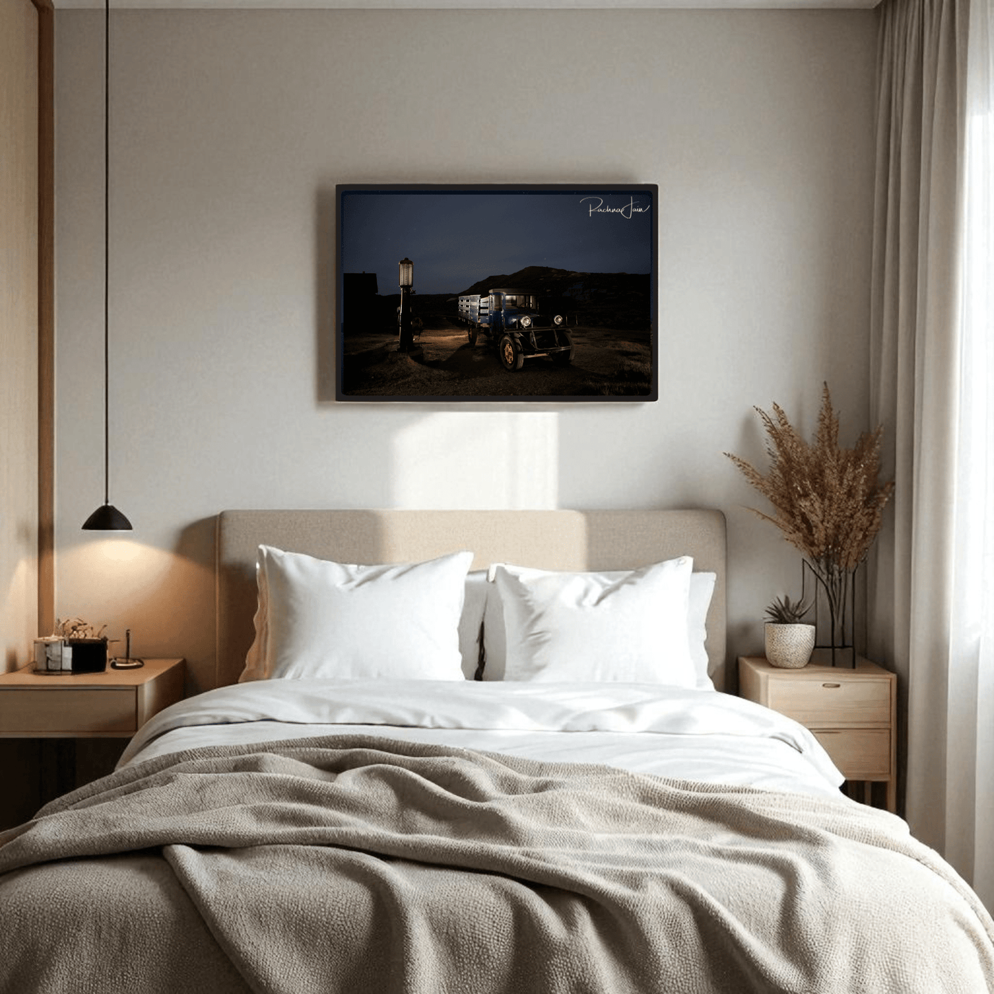 A cozy bedroom with a double bed, white bedding, and light wood furniture features Mirabilia Boutique’s “Abandoned Truck at Bodie State Park | Light-Painted Art Print” above the bed; dried grasses accent the right nightstand.