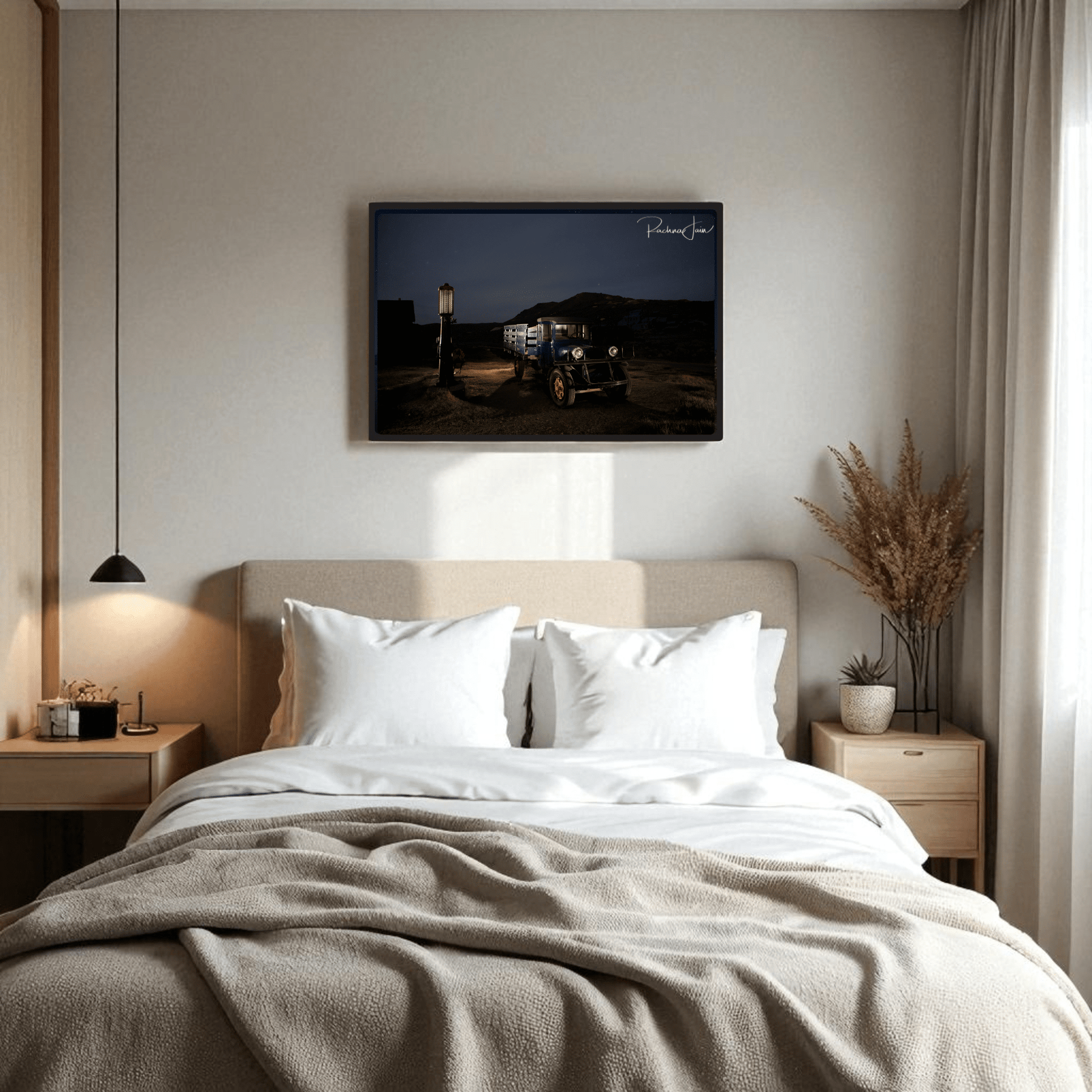 A cozy bedroom with a double bed, white bedding, and light wood furniture features Mirabilia Boutique’s “Abandoned Truck at Bodie State Park | Light-Painted Art Print” above the bed; dried grasses accent the right nightstand.