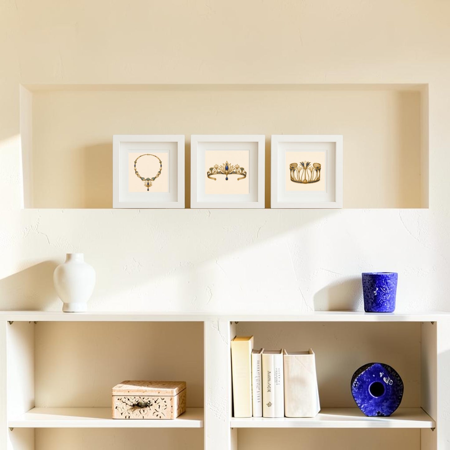 Three framed art pieces from Mirabilia Boutique, including “Adornments of the Nile | Mirabilia Relics” featuring ancient Egypt-inspired jewelry and floral motifs, are displayed in a wall niche above a white shelf holding books, a white vase, a blue cup, a decorative box, and a blue circular object. The scene is softly lit.