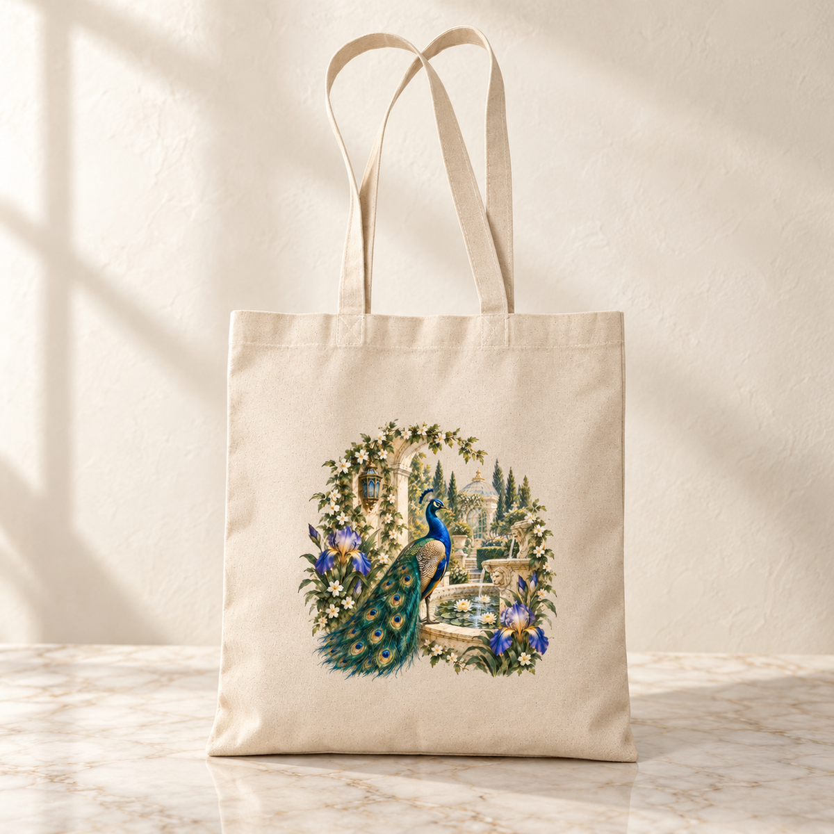 A beige Afternoon in the Peacock Garden Tote from Mirabilia Boutique’s Gilded Reverie collection, adorned with a jeweled peacock illustration surrounded by flowers and greenery, rests on a marble surface against a neutral background.