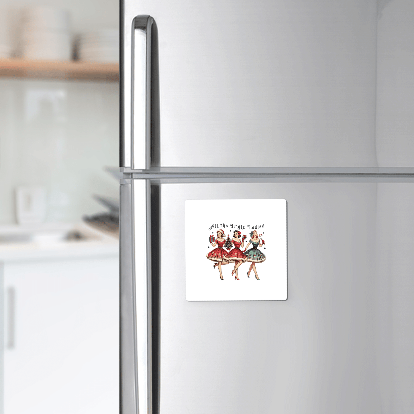 The All the Jingle Ladies Magnet by Mirabilia Boutique, a retro Christmas decor item featuring three women in vintage dresses, is displayed on a stainless steel fridge in a modern kitchen.