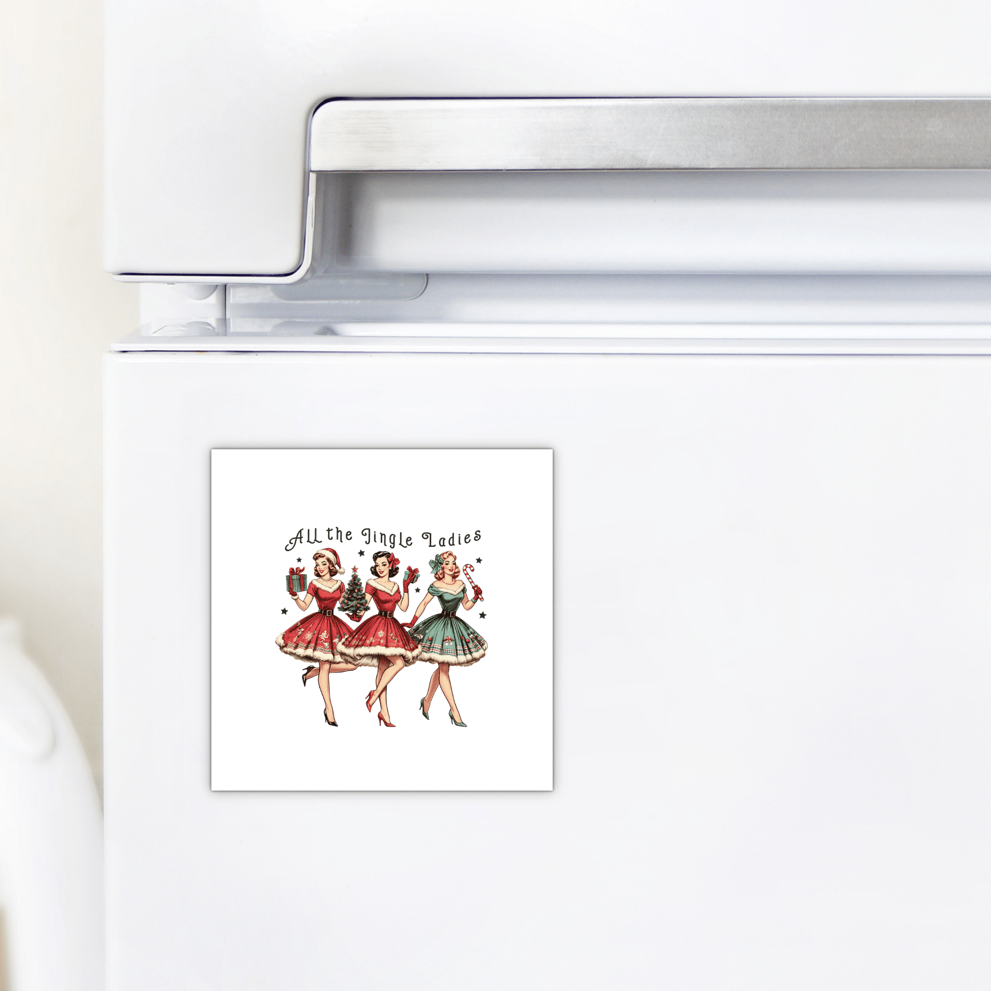 A white fridge displays Mirabilia Boutique's "All the Jingle Ladies Magnet," a retro Christmas decor piece featuring three festive pin-up women holding mugs with the phrase "All the Jingle Ladies" above them.