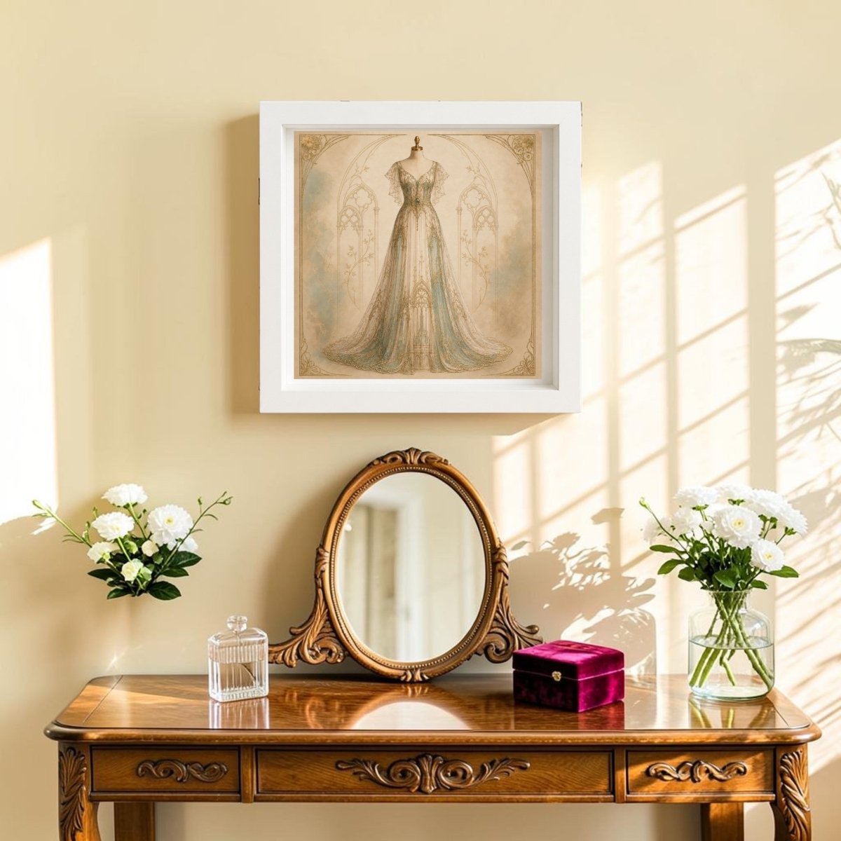 A graceful vanity arrangement sits below the Conservatory Grace | Curated Couture Artwork from Mirabilia Boutique—a framed canvas showcasing a vintage dress. Sunlight streams across the beige wall, illuminating white and red jewelry boxes and vases of white flowers, and casting elegant shadows that highlight the curated, sophisticated interiors.
