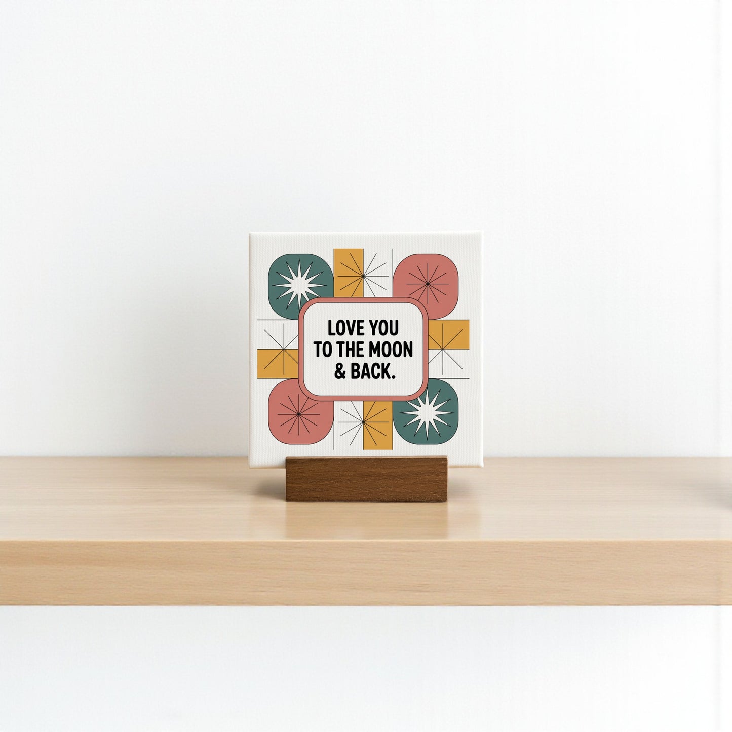 The Mirabilia Boutique "Love You to the Moon & Back" 4x4 Mini Canvas Retro Sign features colorful geometric shapes on a plain white background, set on a wooden stand—a charming love gift with nostalgic decor vibes.