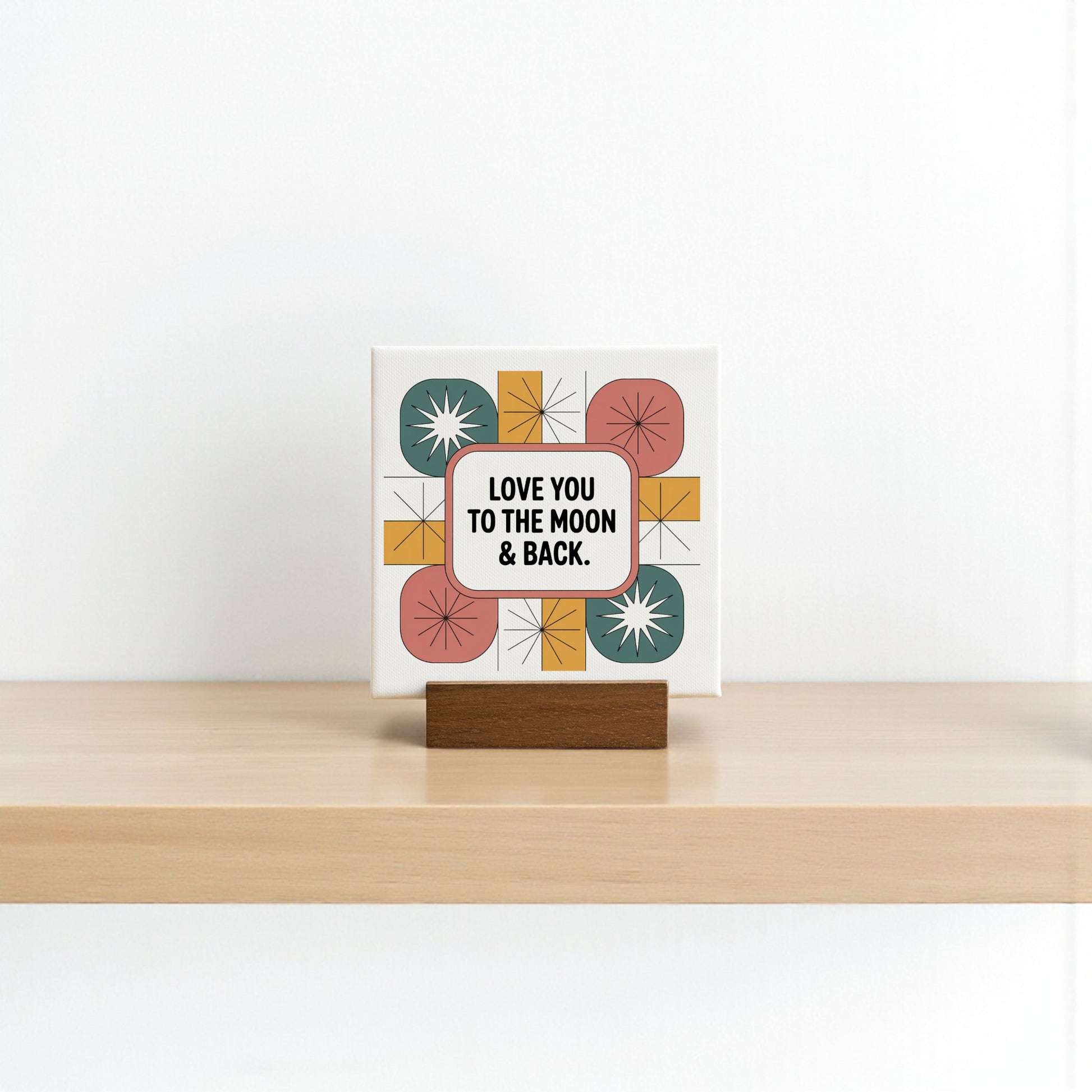 The Mirabilia Boutique "Love You to the Moon & Back" 4x4 Mini Canvas Retro Sign features colorful geometric shapes on a plain white background, set on a wooden stand—a charming love gift with nostalgic decor vibes.