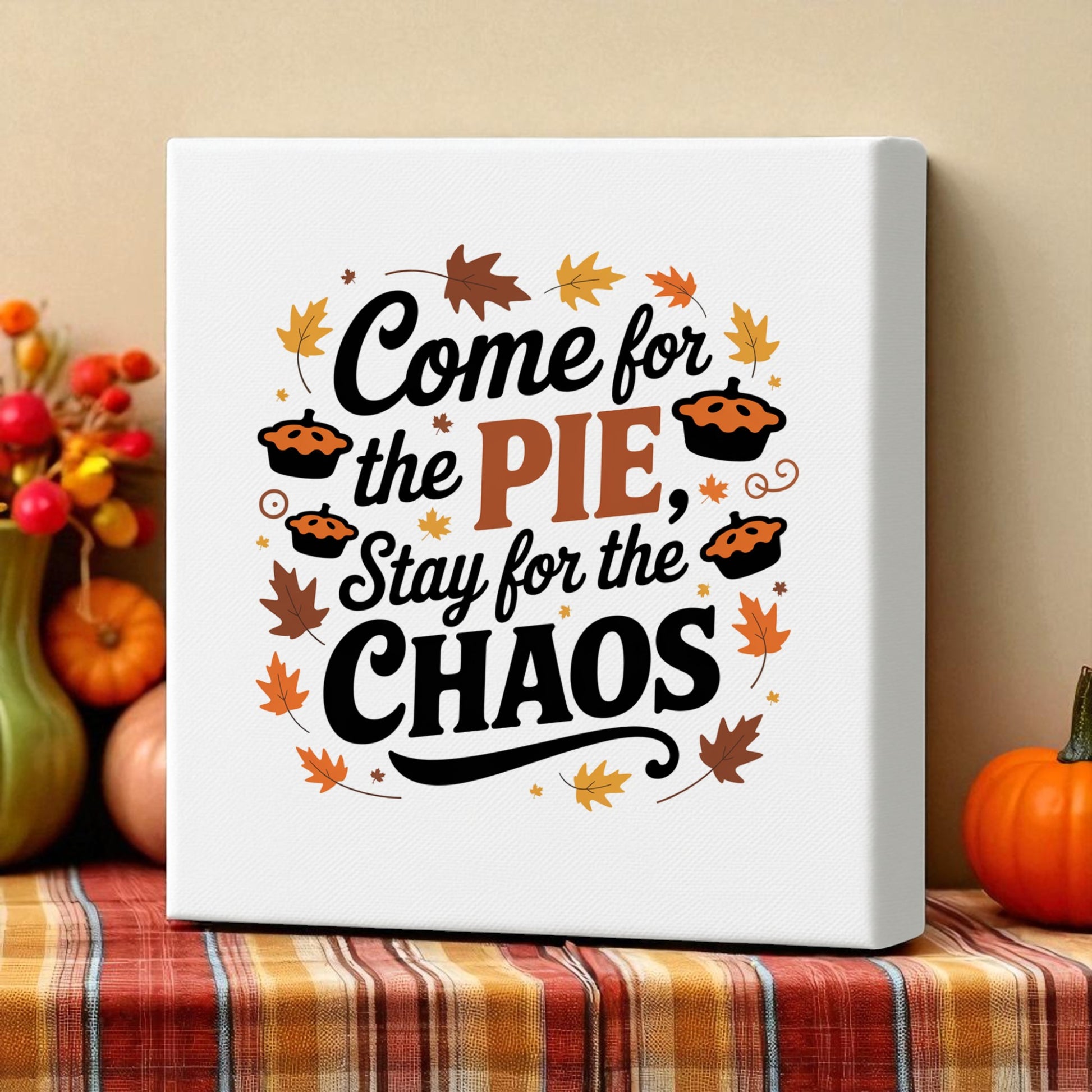 The Mirabilia Boutique's "Come for the Pie Chaos Art" funny Thanksgiving canvas features autumn leaves and pies, perfect as festive decor on a plaid tablecloth beside pumpkins and fall foliage.