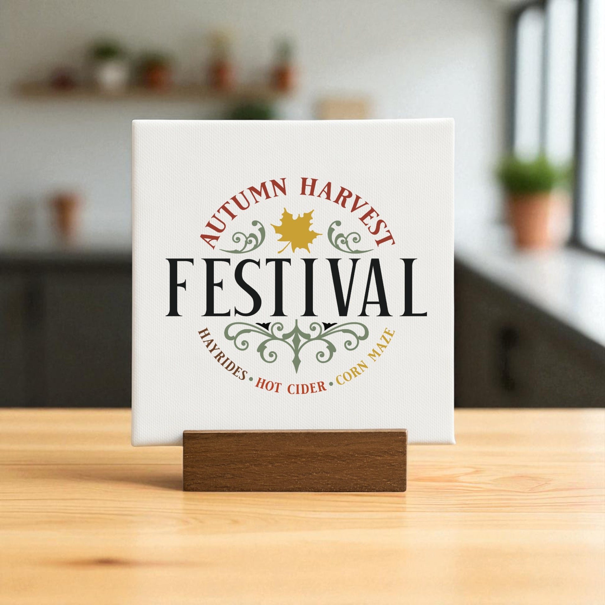 The Autumn Harvest Festival Mini Sign by Mirabilia Boutique is a 4x4 rustic accent featuring festive text and leaves on a wooden stand—ideal fall decor for your kitchen or home. Blurred shelves and potted plants complete the cozy backdrop.