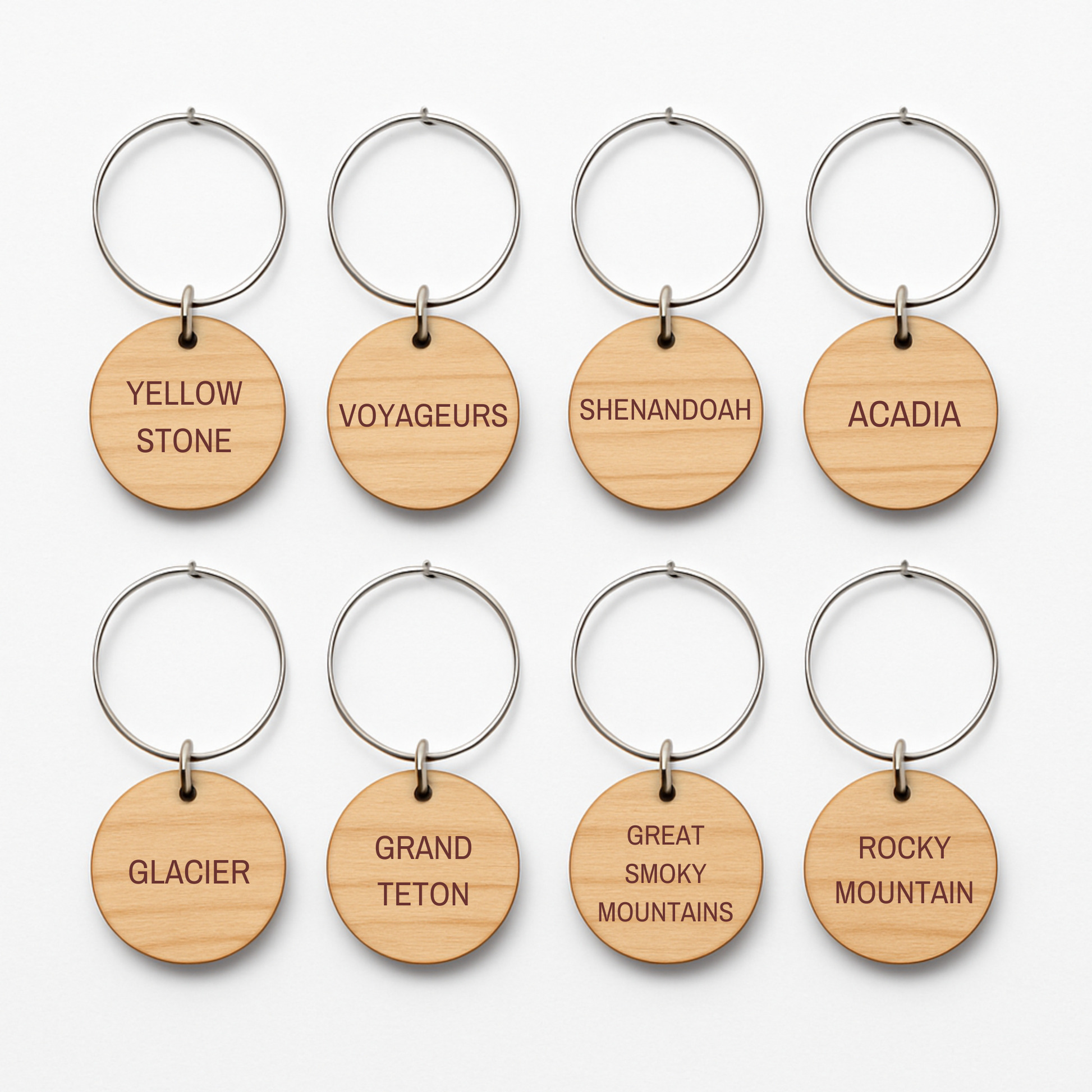 Mirabilia Boutique's Autumn Lodge National Parks Wine Charms feature eight round wooden keychains with metal rings, each engraved with a U.S. national park—perfect rustic accents for your fall gatherings.