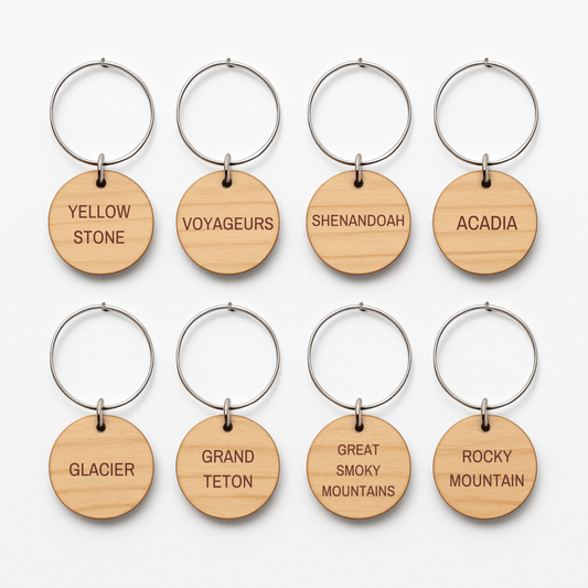 Mirabilia Boutique's Autumn Lodge National Parks Wine Charms feature eight round wooden keychains with metal rings, each engraved with a U.S. national park—perfect rustic accents for your fall gatherings.