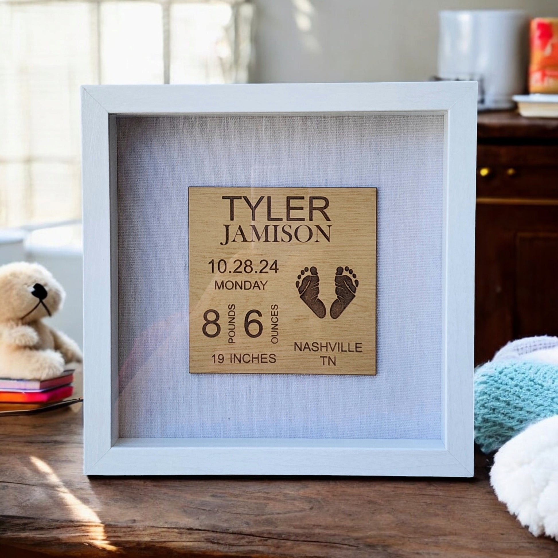 Crafted by Mirabilia Boutique, the Baby Birth Stats Nursery Sign is a personalized keepsake that beautifully showcases Tyler Jamison's birth announcement details. Born on October 28, 2024, in Nashville, TN, it includes his weight, length, and tiny footprints. Elegantly set on a wooden table beside a stuffed toy and blanket, it's perfect for any nursery display.