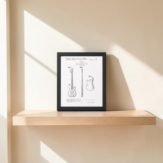 The Mirabilia Boutique Bass Guitar Patent Print on metal (8x10) adds music-themed decor to your wall, displayed on a light wood floating shelf against a beige background, with sunlight creating striking angular shadows.