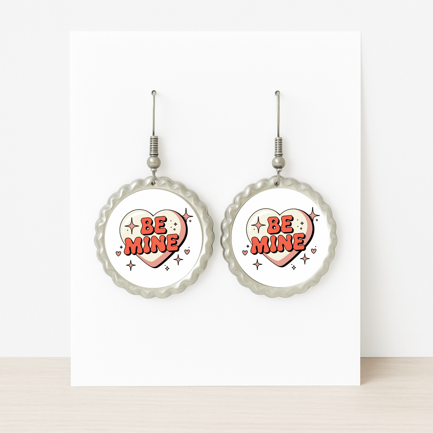 Mirabilia Boutique’s Be Mine Heart Earrings feature a retro scalloped design with bold red “BE MINE” hearts—displayed on a white card, they make a cute Valentine jewelry gift.
