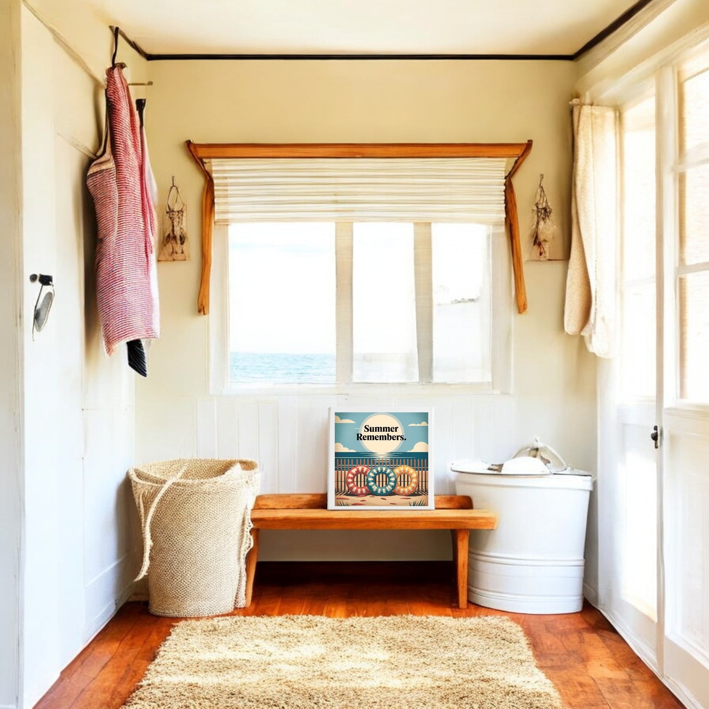 A bright room with wooden floors features a woven laundry basket, white bin, and wooden bench. The "Summer Remembers Canvas Wall Art – Coastal Nostalgia" by Mirabilia Boutique adds beach cottage charm beneath a sunlit window.