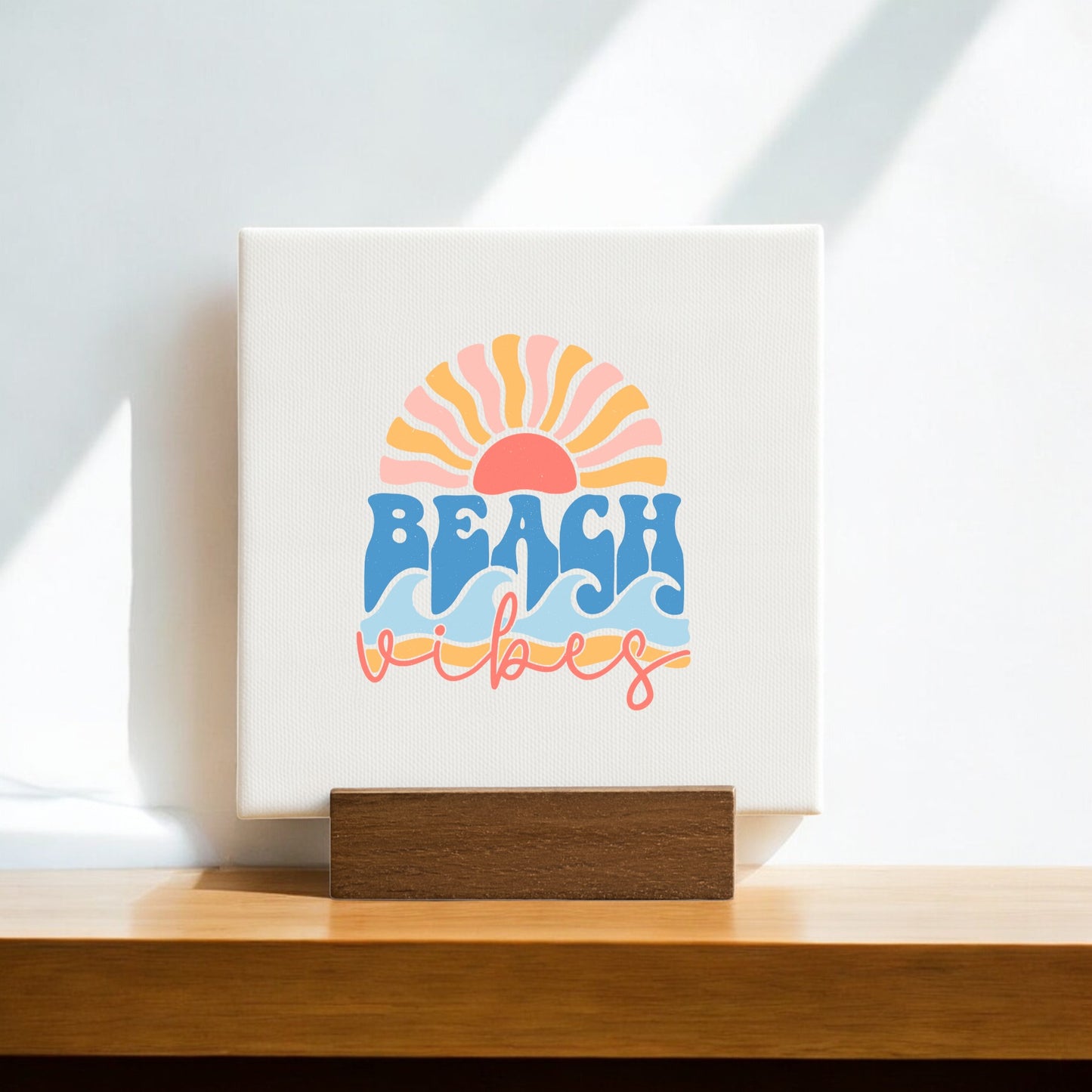 The Beach Vibes Mini Canvas – Retro Summer Desk Art by Mirabilia Boutique features a vibrant sun rising over waves and "BEACH vibes" in bold blue and cursive pink—perfect as a summer gift or beach-themed decor. Sunlight casts shadows on the white background.