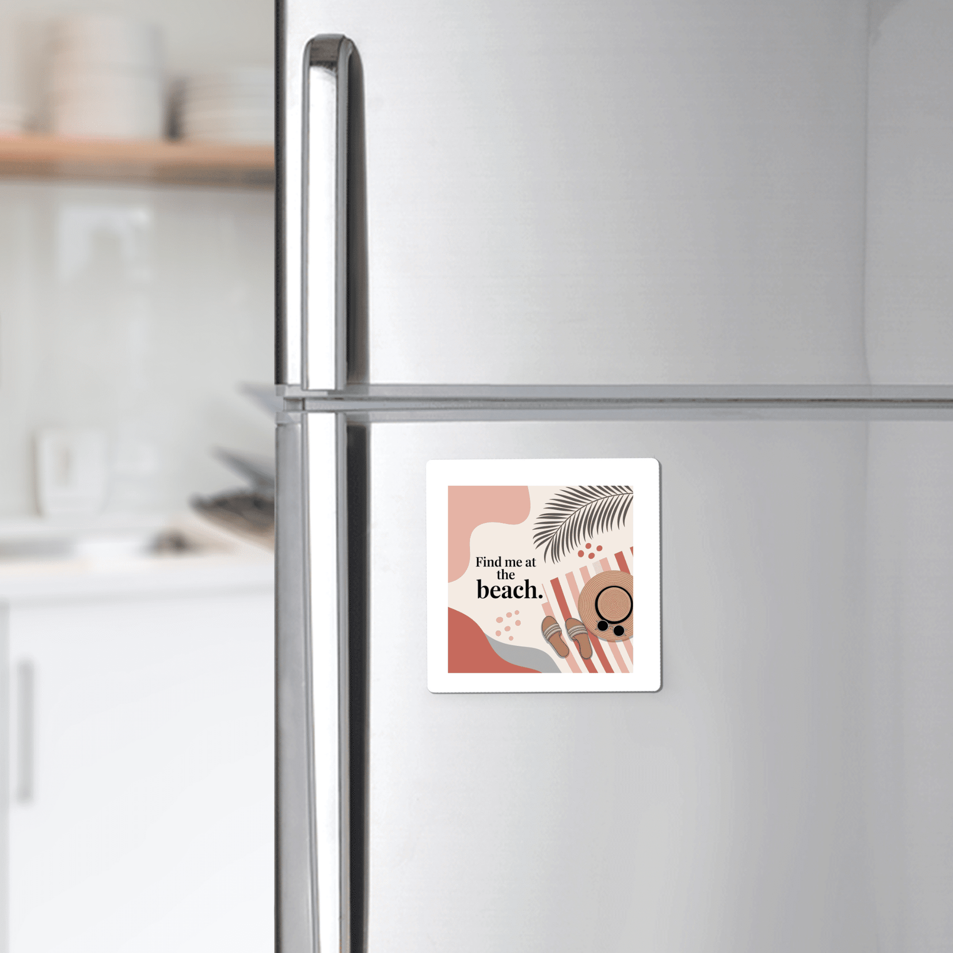 The Find Me at the Beach Magnet – Coastal Summer Aesthetic by Mirabilia Boutique features sunglasses, a palm leaf, sandals, and “find me at the beach” text on a silver fridge, adding coastal charm to a modern white kitchen.