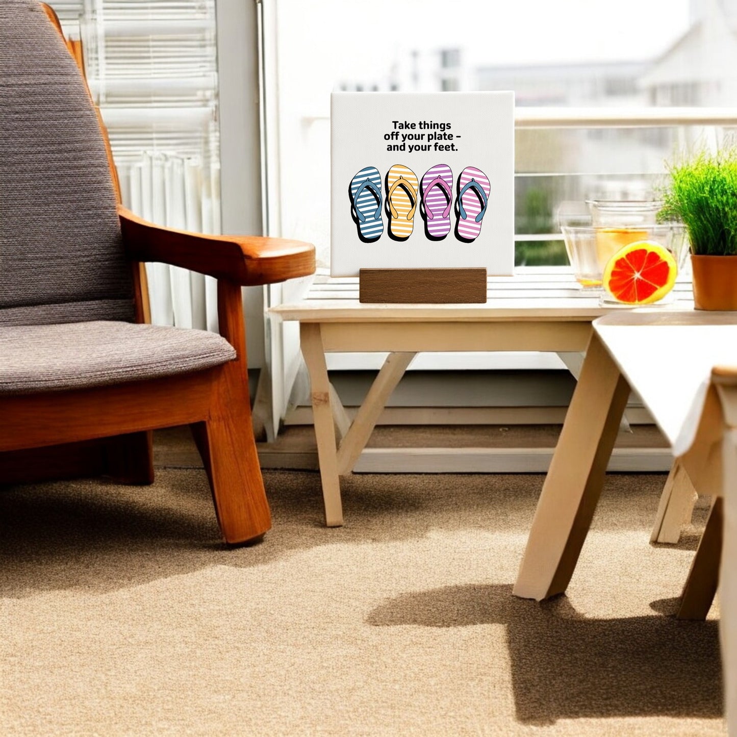 A table and chair display features the Mirabilia Boutique "Take Things Off Your Feet" 4x4 Summer Sign with Stand, decorated with flip-flop artwork and seasonal flair.