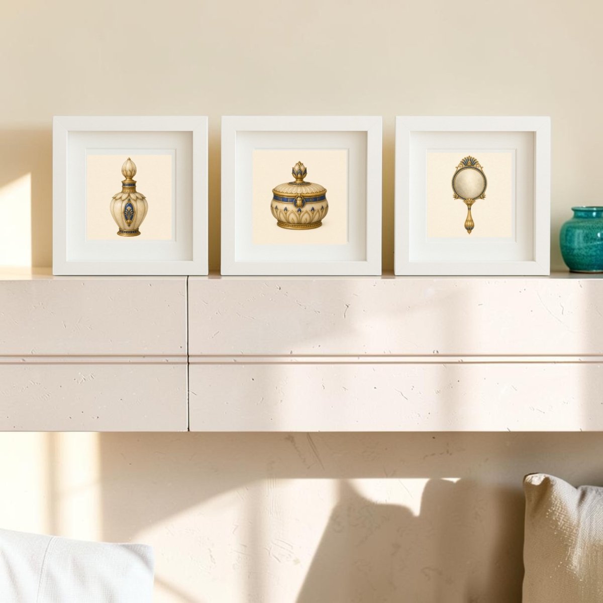 Three framed pictures from the “Beauty Rituals of the Nile Relics” collection by Mirabilia Boutique, featuring ornate gold and ivory artifacts reminiscent of ancient Nile relics, are displayed on a light-colored mantel. Sunlight casts gentle shadows across the scene, highlighting a small teal vase on the right side.