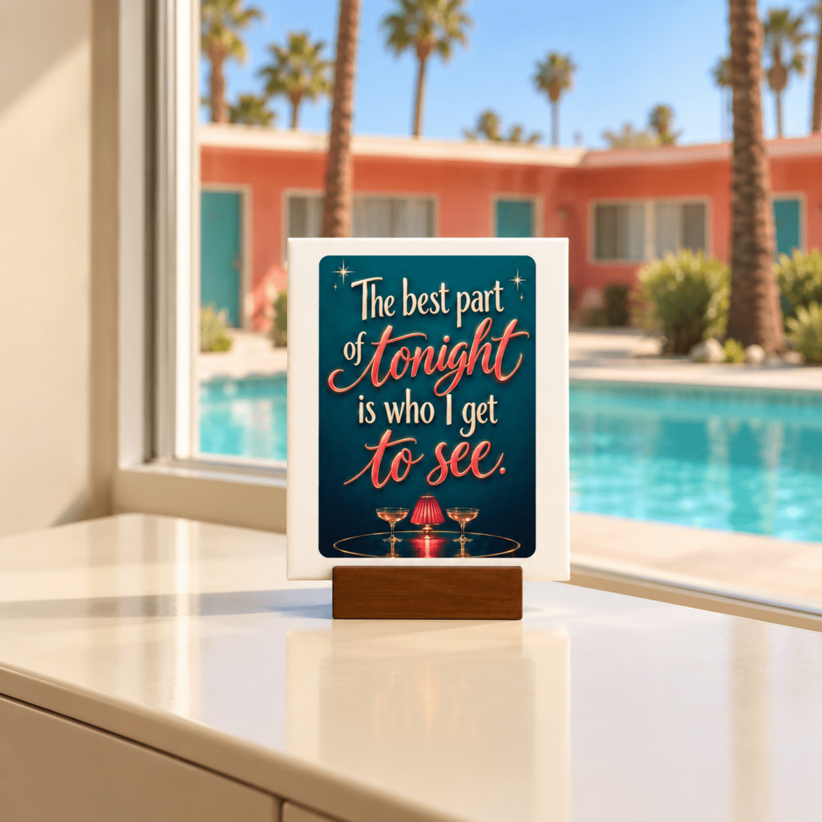 The Best Part of Tonight Mini Sign | Chrome & Starlight by Mirabilia Boutique sits on a window ledge, featuring the phrase “The best part of tonight is who I get to see,” and a backdrop of a pool, palm trees, and colorful buildings.