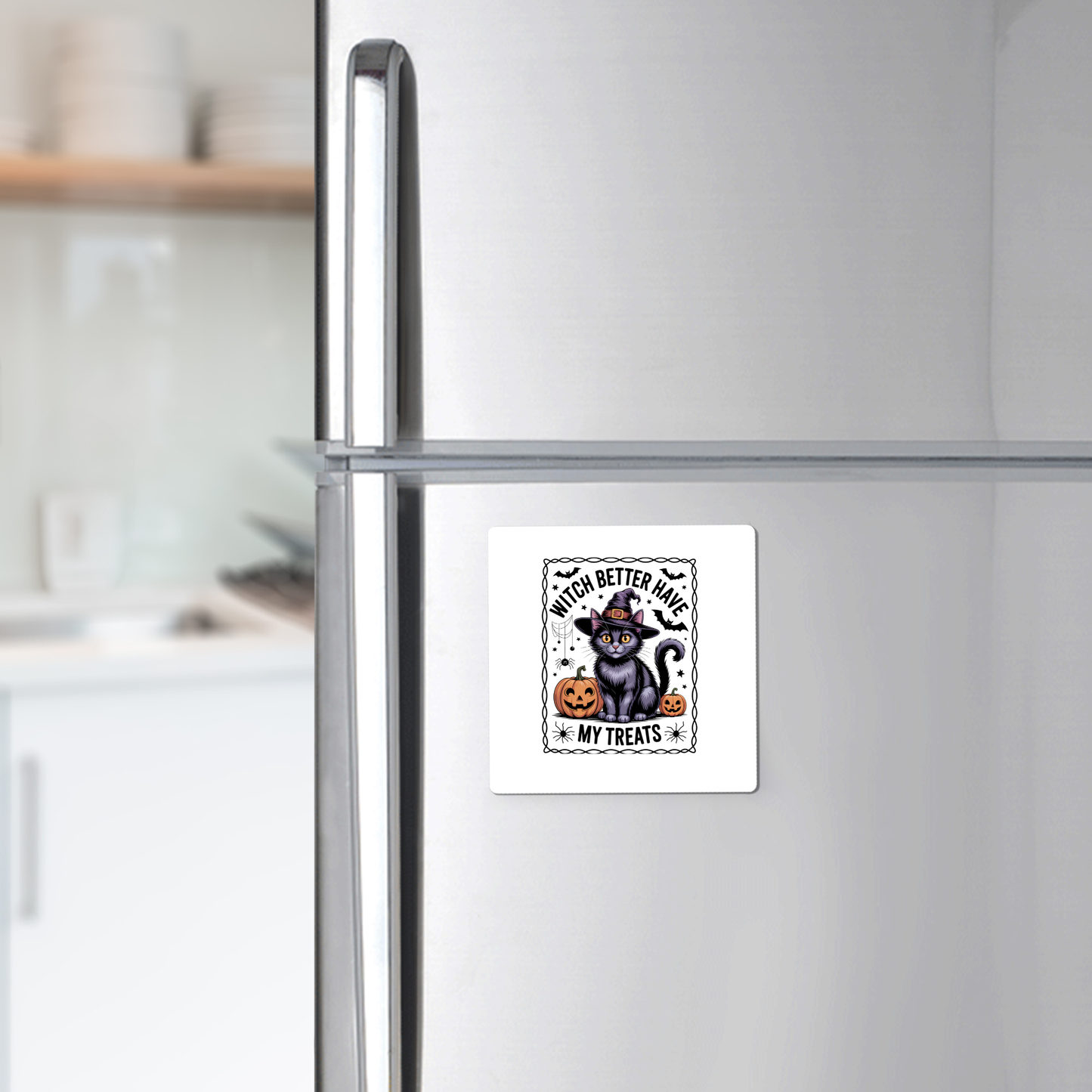 A refrigerator displays the Mirabilia Boutique Black Cat Witch Magnet, featuring a cat in a witch hat, pumpkin, and "Witch Better Have My Treats" text. Dishes are visible on the kitchen counter in the background.