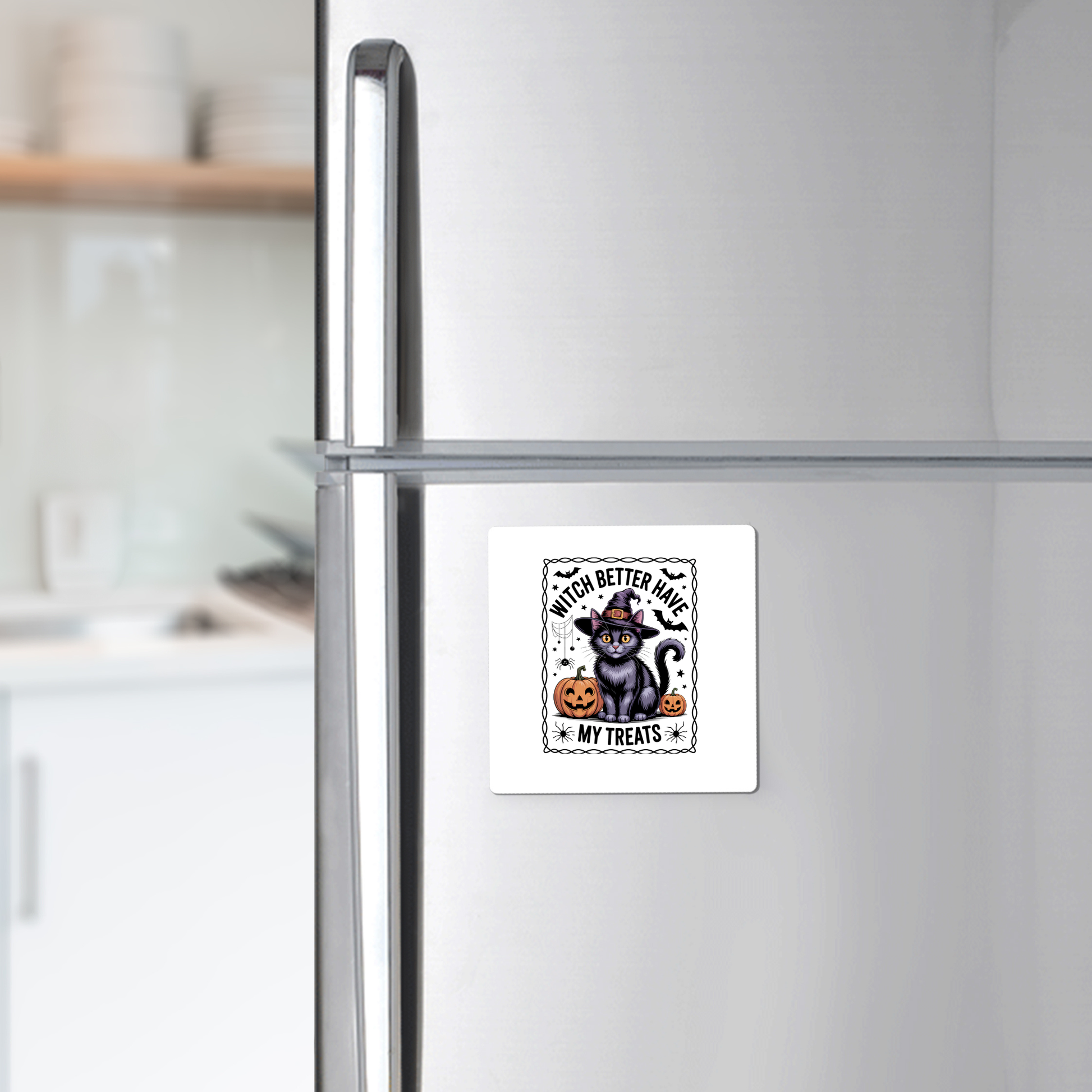 A refrigerator displays the Mirabilia Boutique Black Cat Witch Magnet, featuring a cat in a witch hat, pumpkin, and "Witch Better Have My Treats" text. Dishes are visible on the kitchen counter in the background.
