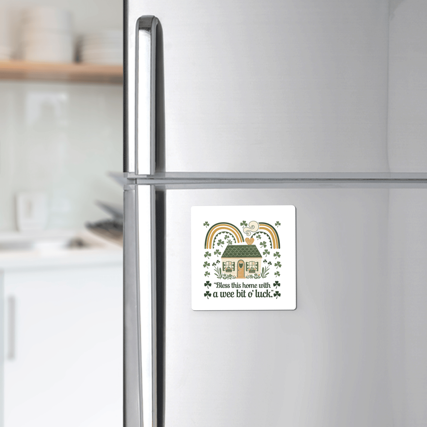 The Mirabilia Boutique Wee Bit o’ Luck Irish Home Magnet features rainbows, shamrocks, and a cozy cottage with the phrase “Bless this home with a wee bit o’ luck”—a charming touch for any stainless steel fridge. A softly blurred kitchen appears in the background.