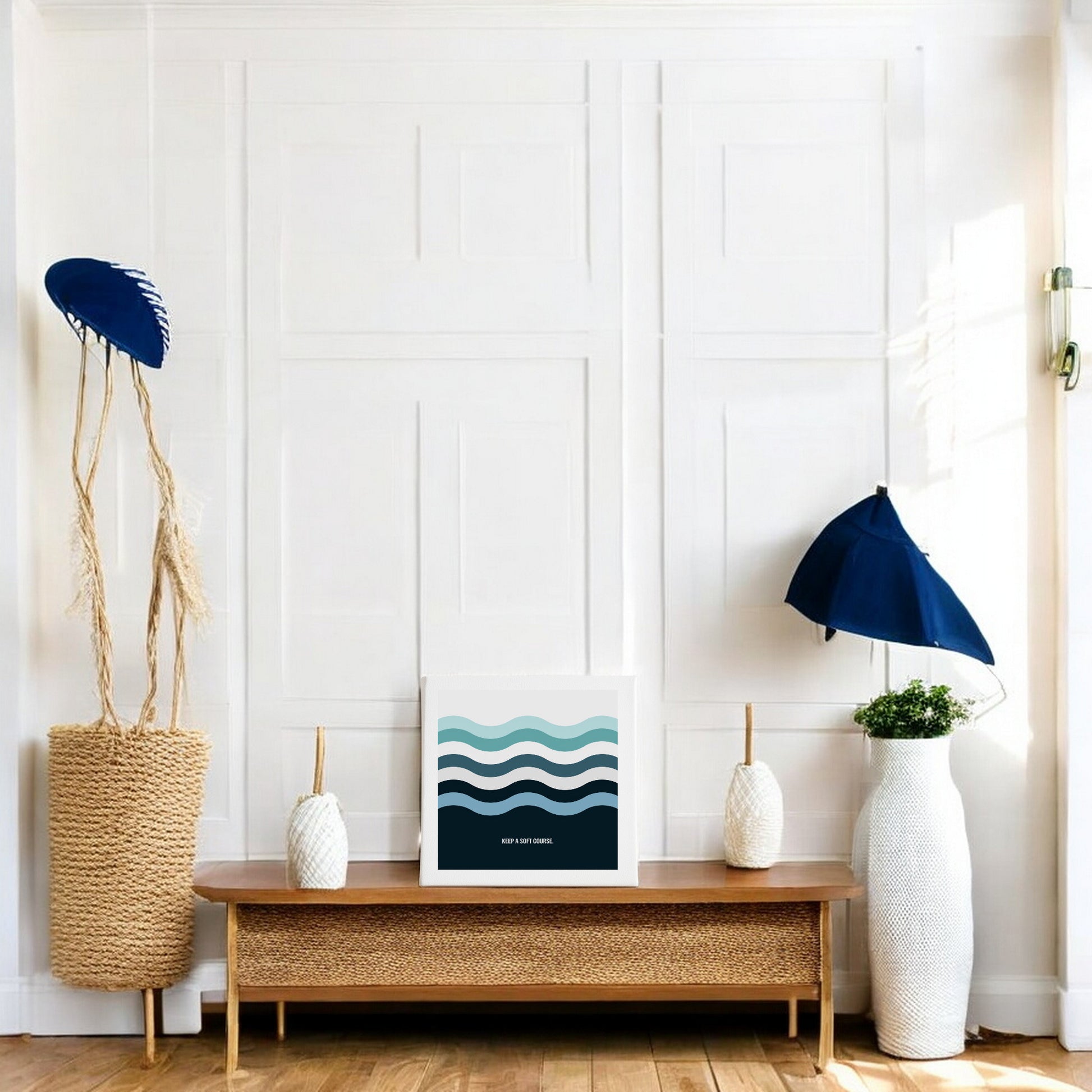 A modern, minimal living space with calming decor: a wooden bench, woven baskets, white vases, and two blue umbrellas. On the bench leans Mirabilia Boutique's "Keep a Soft Course" 8x8 minimal ocean art canvas sign with wavy blue lines.