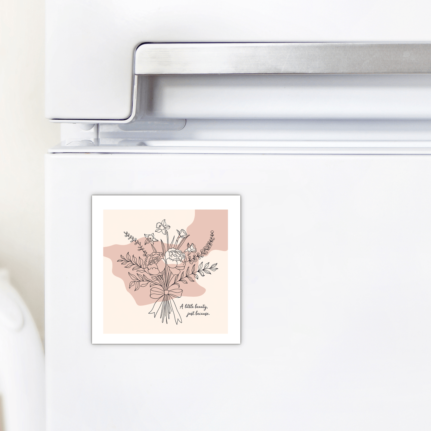 A white fridge with Mirabilia Boutique’s “A Little Beauty Magnet – Just Because Floral Gift,” featuring a flower bouquet line drawing on beige and pink with the phrase “A little beauty goes a long way.” Ideal as a thinking of you gift.