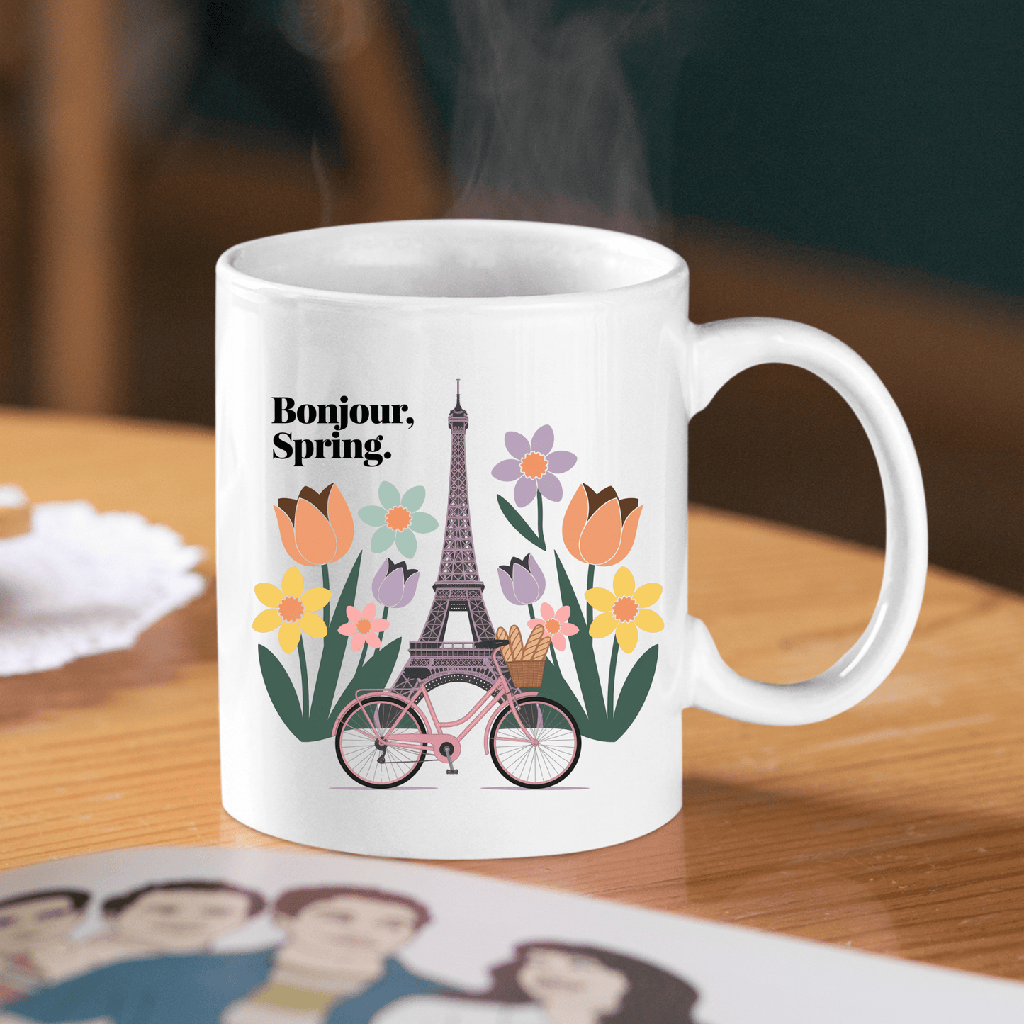Sip your Parisian coffee from the Mirabilia Boutique Bonjour Spring Paris Mug – Eiffel Tower & Florals, featuring “Bonjour, Spring.” with vibrant blooms and a pink bicycle—perfect for brightening your mornings.