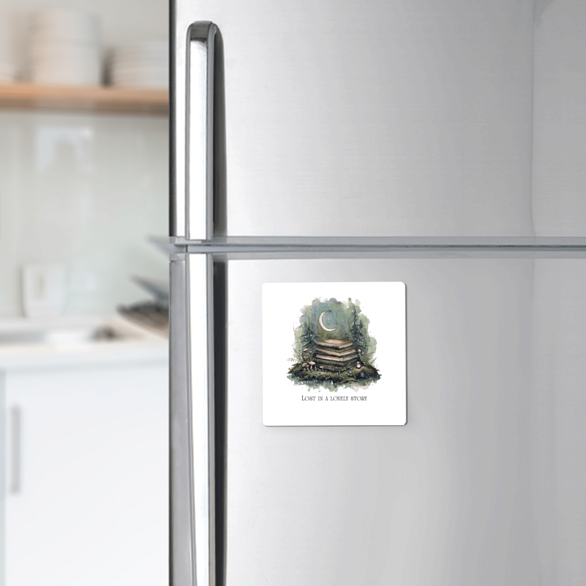 Add a background of a blurred kitchen. The Lost in a Lovely Story Book Lover Magnet by Mirabilia Boutique adorns the refrigerator—a square, handcrafted magnet illustrated with stacked books, greenery, and a crescent moon. It features the phrase “Love is a lovely story,” making it an ideal literary gift for any book enthusiast.